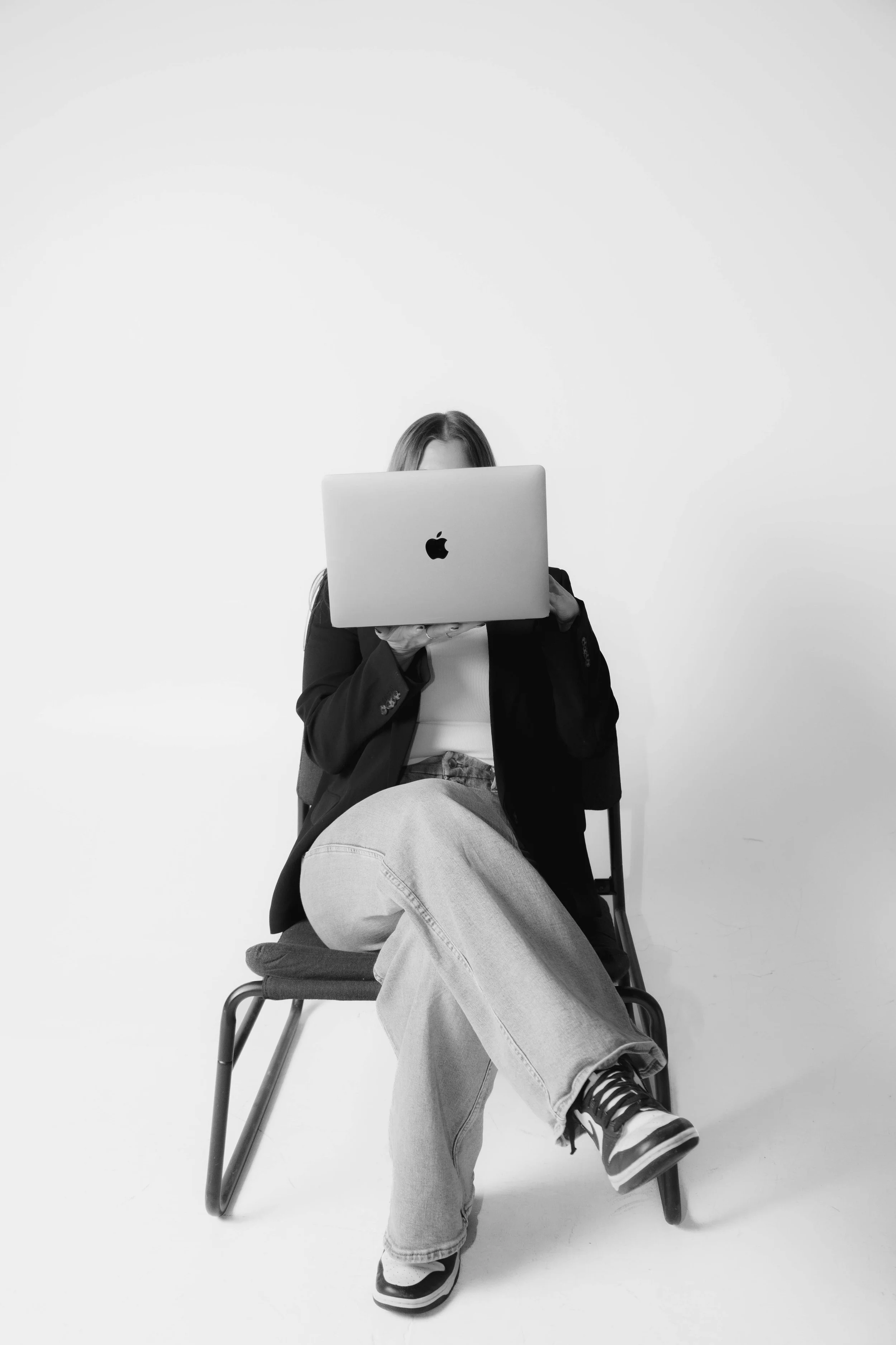 Group of women and girls smiling and laughing outside in a yard with greenery, participating in a game or activity on a sunny day.