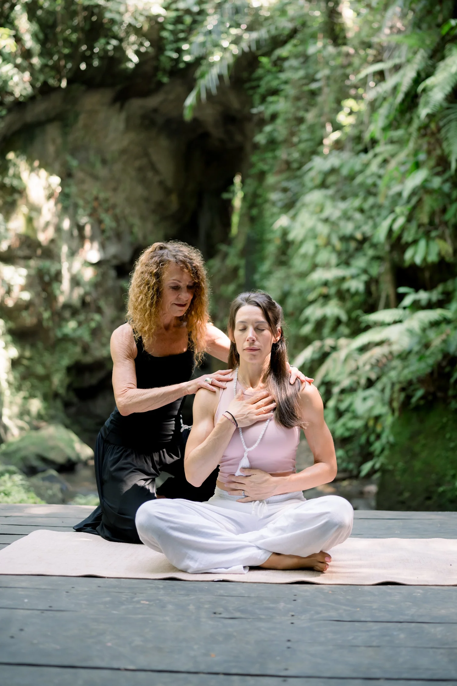 Dawn guiding a woman through a breathing practice in the jungle
