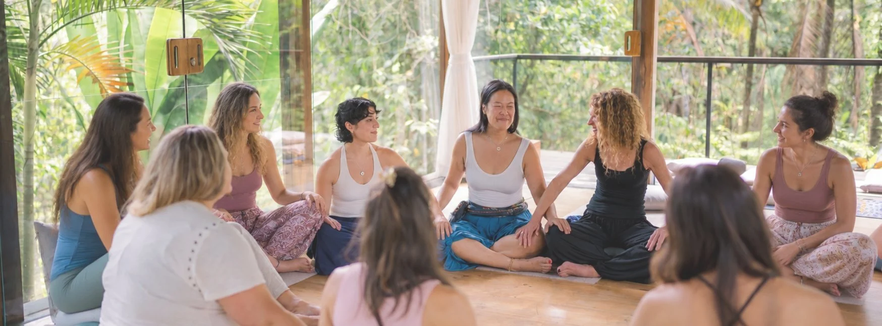 Women sitting together in a breathwork circle surrounded by jungle