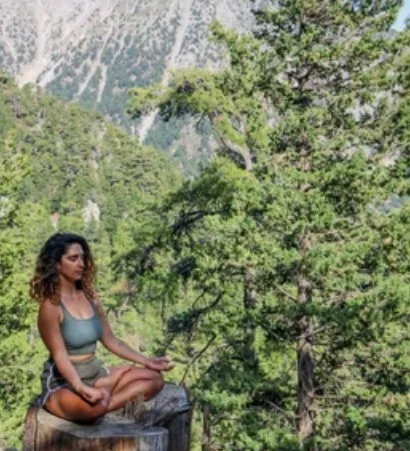 Woman meditating on a tree stump in the mountains