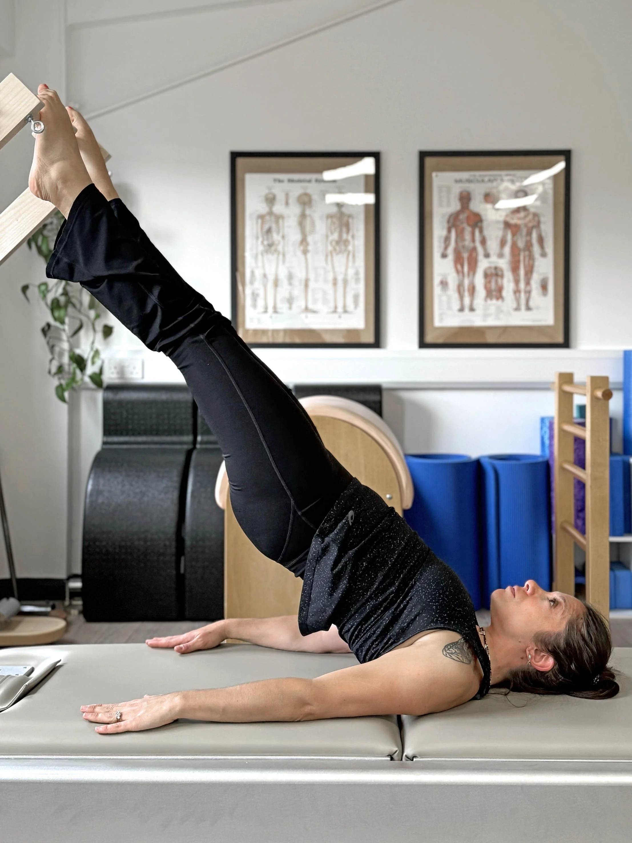 One of our experienced teachers practicing her parakeet exercise on the push through bar on the tower in our beautiful and airy Classical Pilates studio in Clapham North.