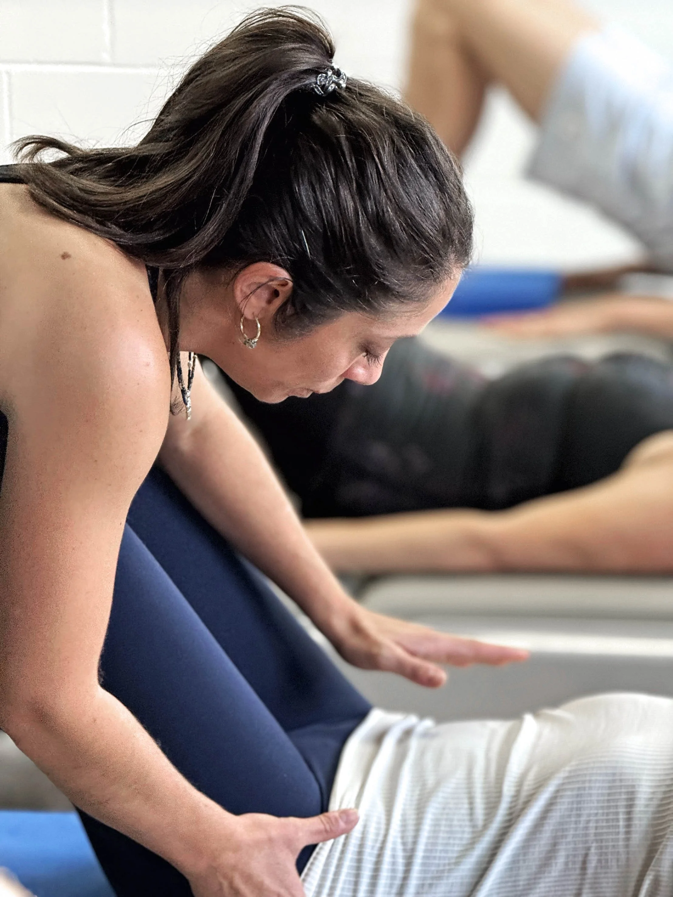 One of our main teachers adjusting a participant in one of our many beginner Pilates group classes.