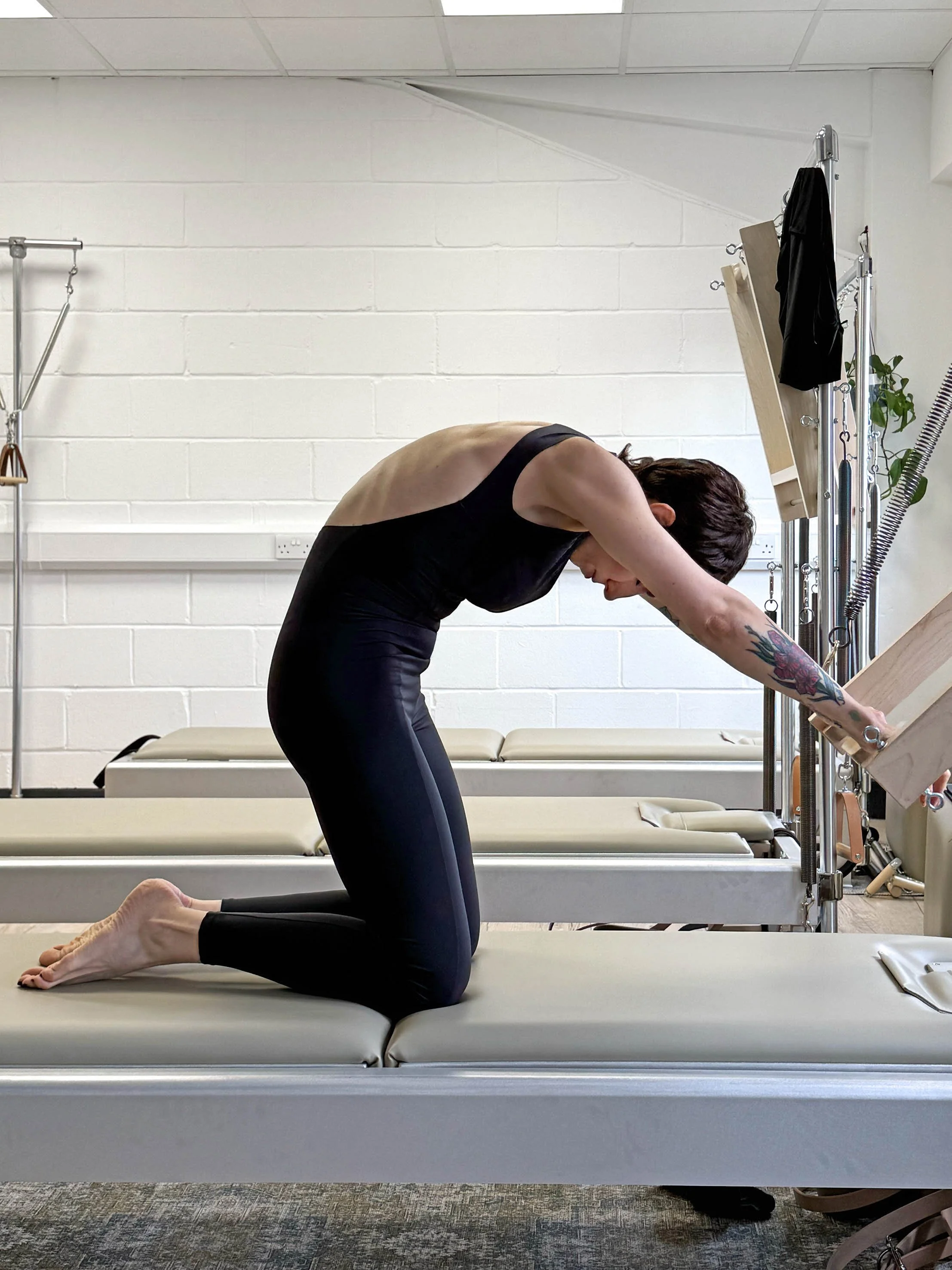 One of our experienced teachers practicing her cat on the push through bar on the tower in our beautiful and airy Classical Pilates studio in Clapham North.