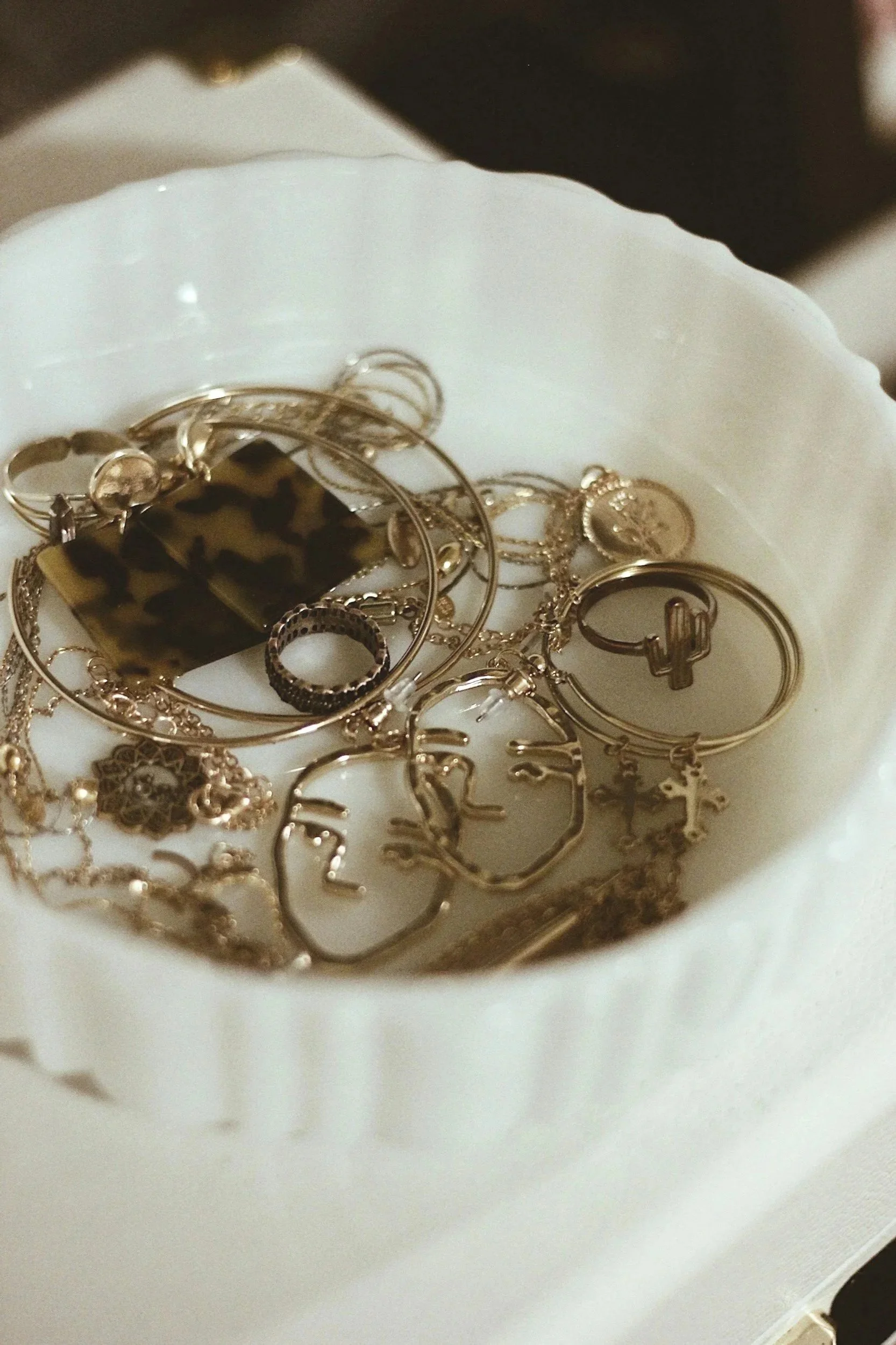 white dish containing gold jewelry