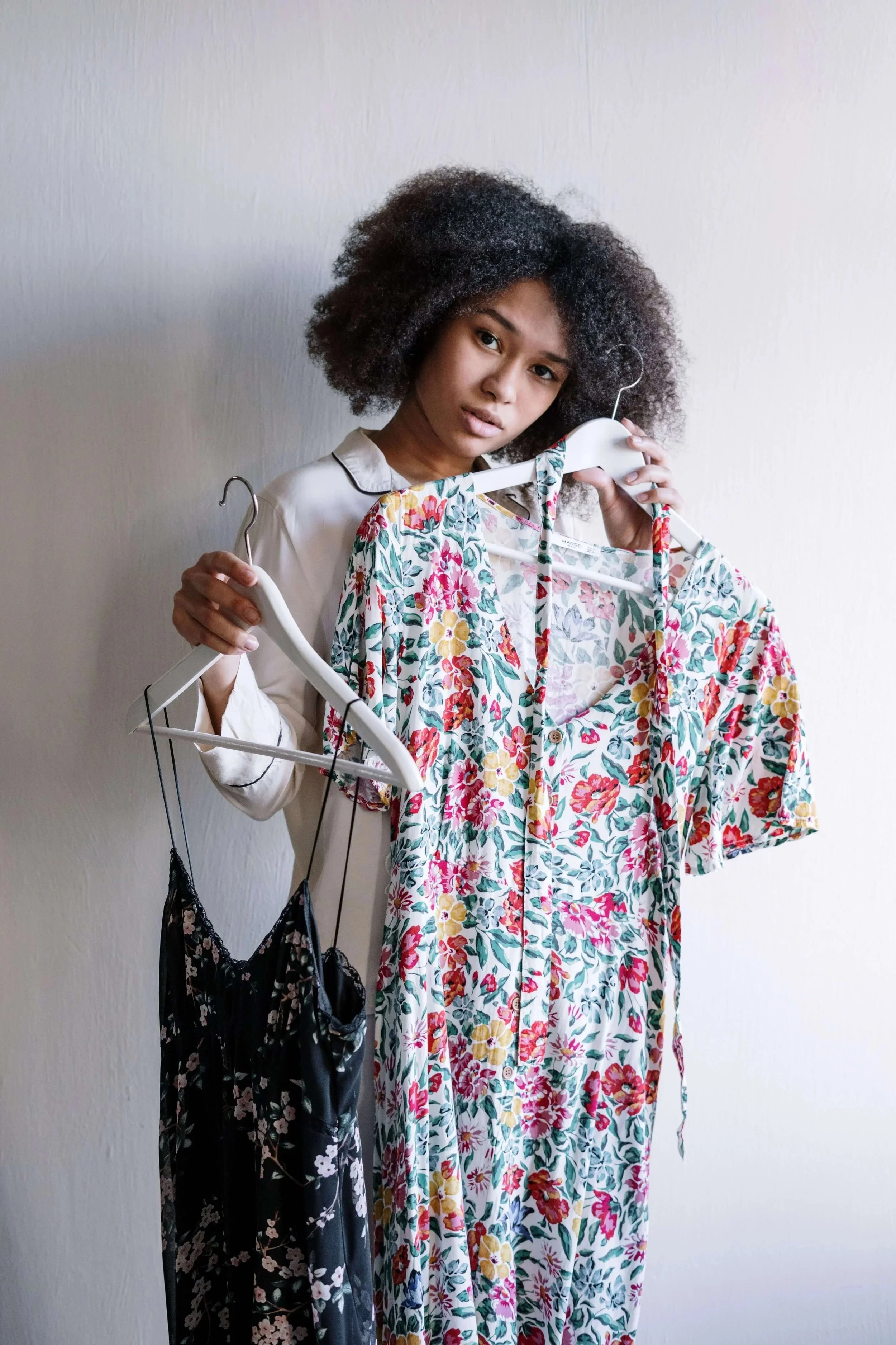 a woman deciding whether to keep two summer dresses