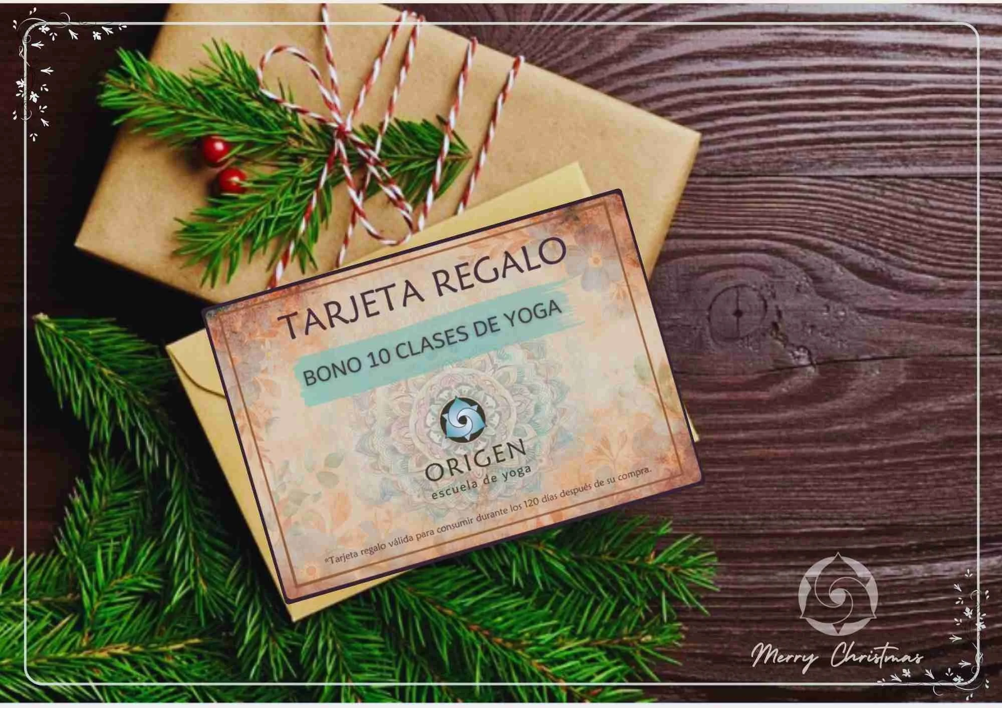 Tarjeta de regalo para 10 clases de yoga de la escuela 'Origen' colocada sobre una caja de regalo envuelta en papel kraft, adornada con ramas de pino y pequeñas bayas rojas, en una superficie de madera.