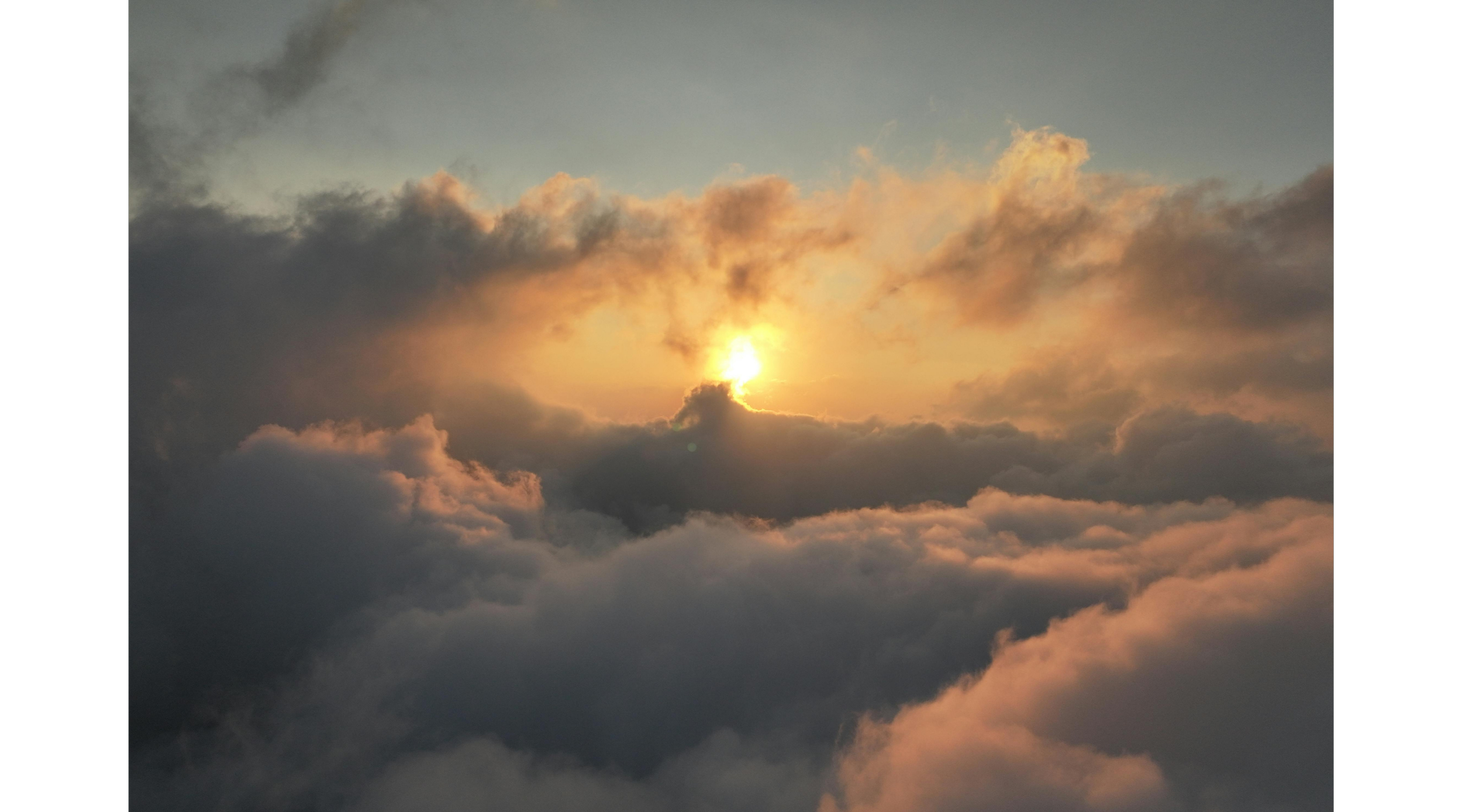 A painting of a serene sky with fluffy clouds surrounding a soft glowing sun.