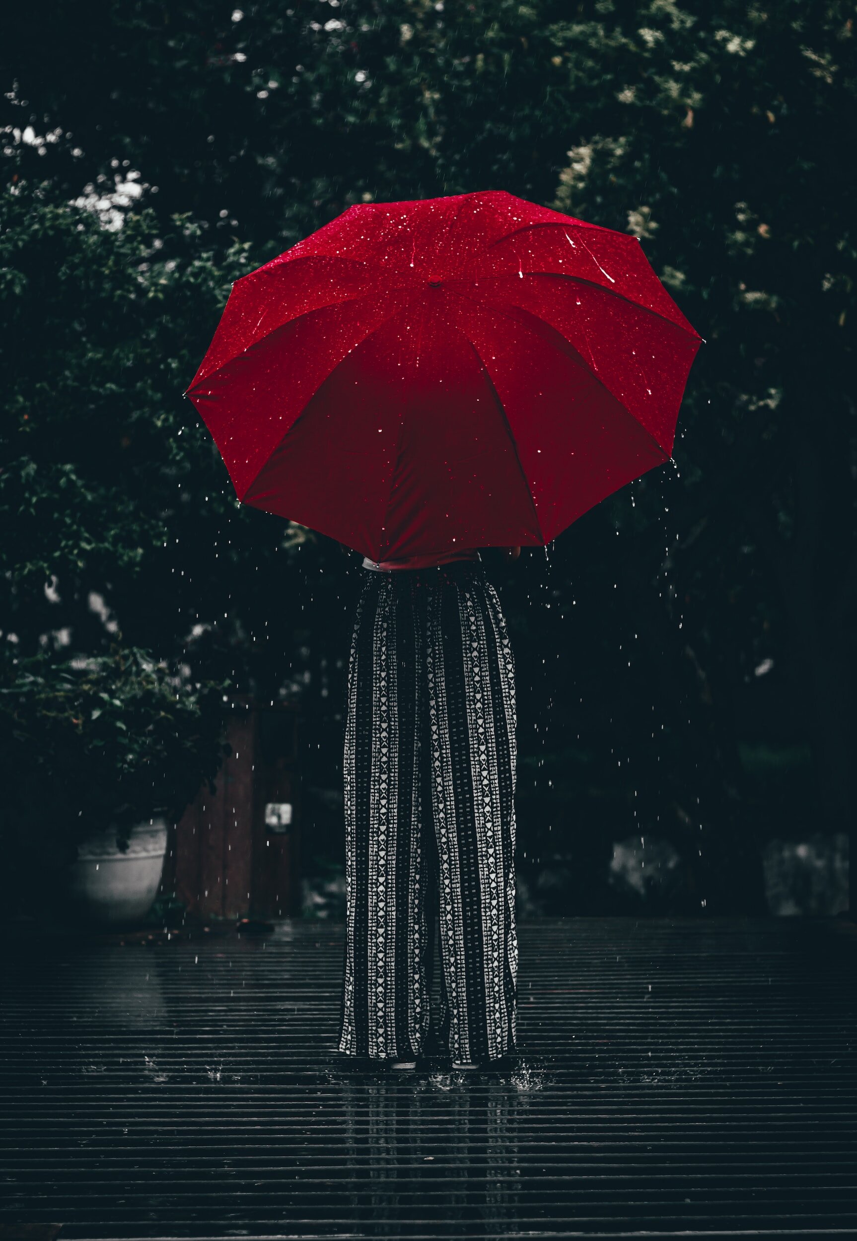 woman from behind holding an red umbrella, raining