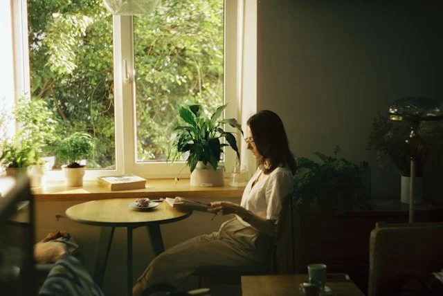 woman-in-white-dress-shirt-sitting-on-chair-near-window-during-daytime
