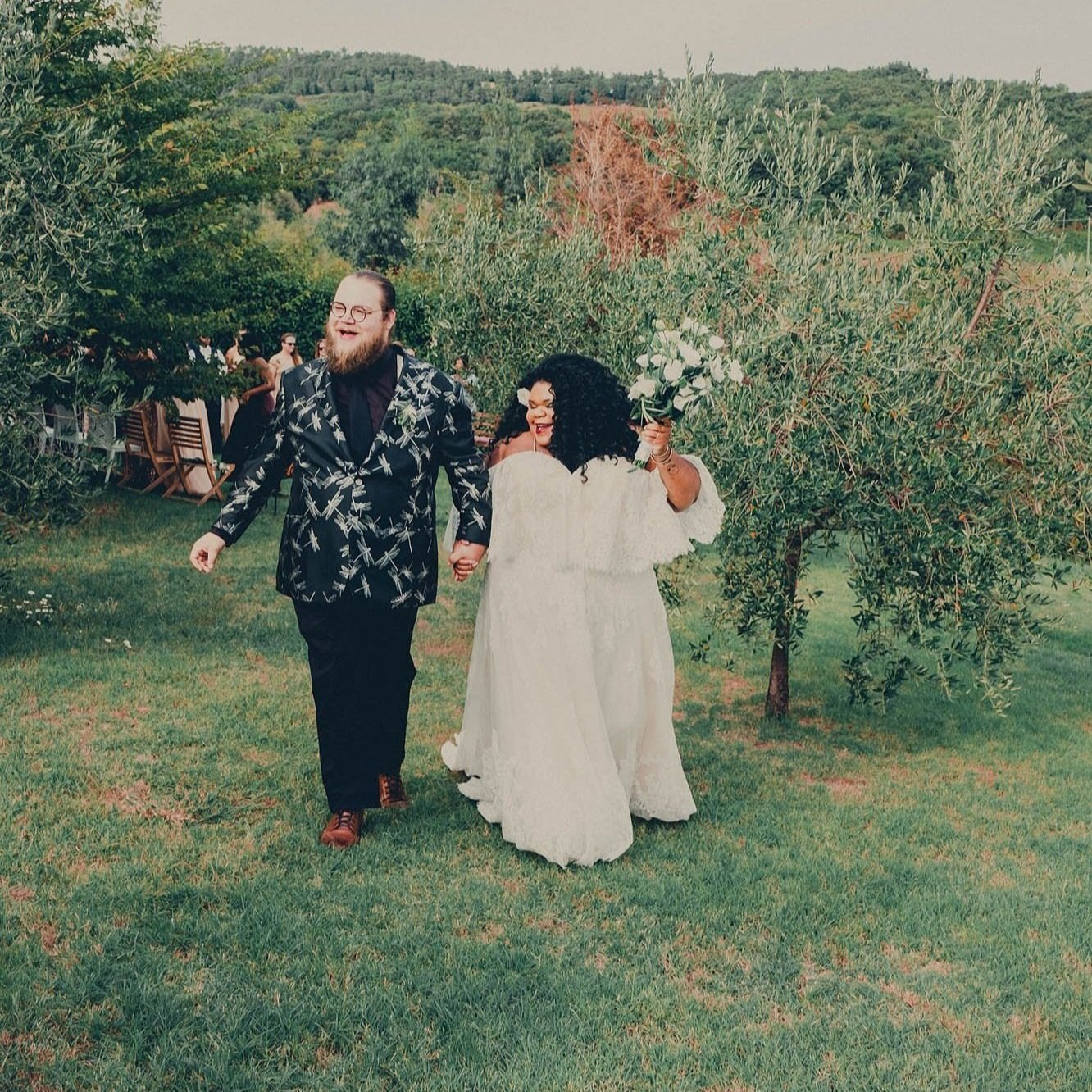 newlyweds walk through a vineyard smiling taken by Sharma Shari Photography