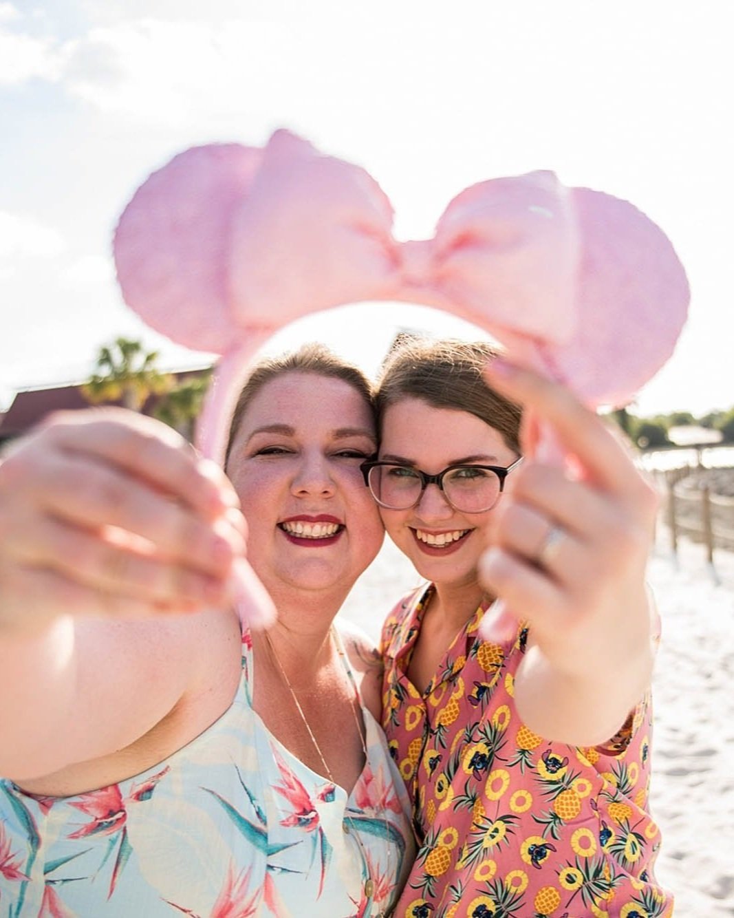 engaged queer couple hold each other close while holding up minnie mouse ears taken by Sharma Shari Photography