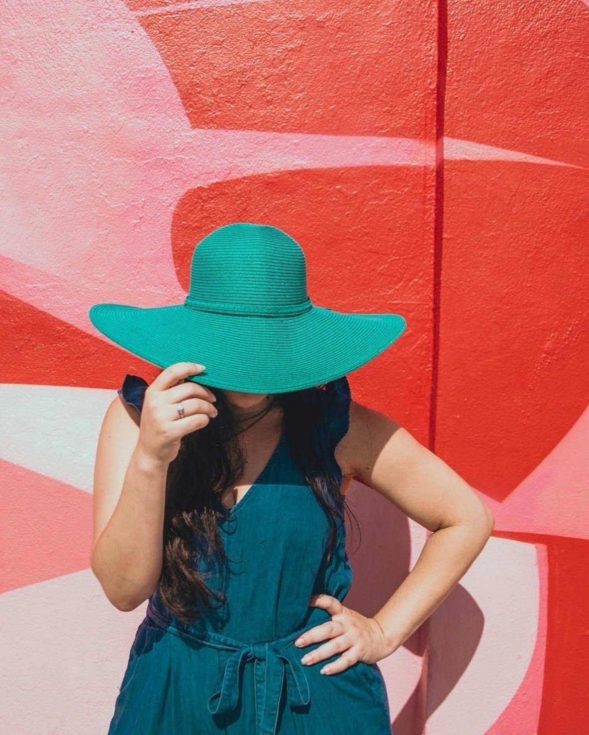 portrait of content creator in front of art mural with teal hat tipped on her head taken by Sharma Shari Photography