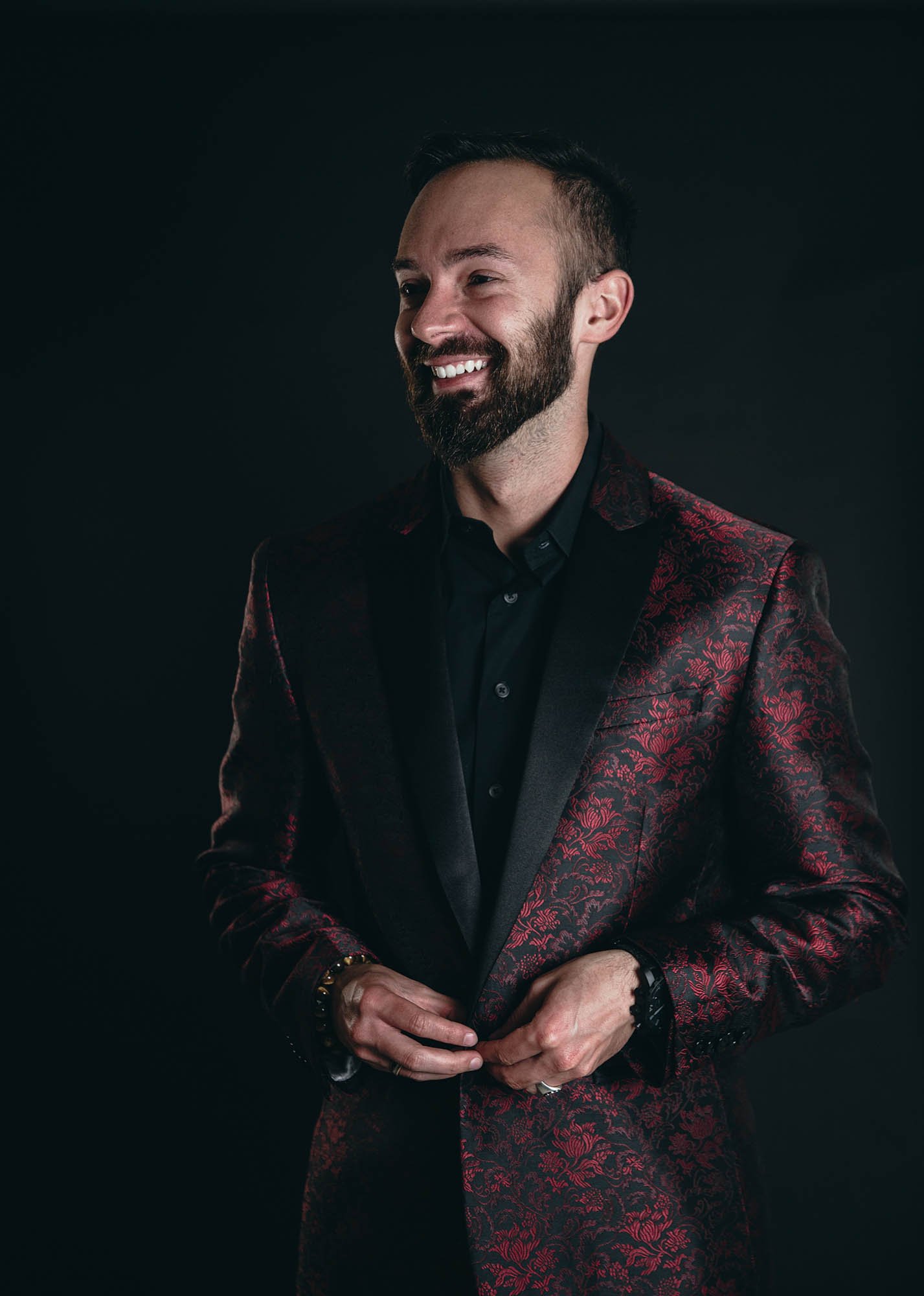 headshot of a small business owner in ornate red and black blazer against gray background taken by Sharma Shari Photography