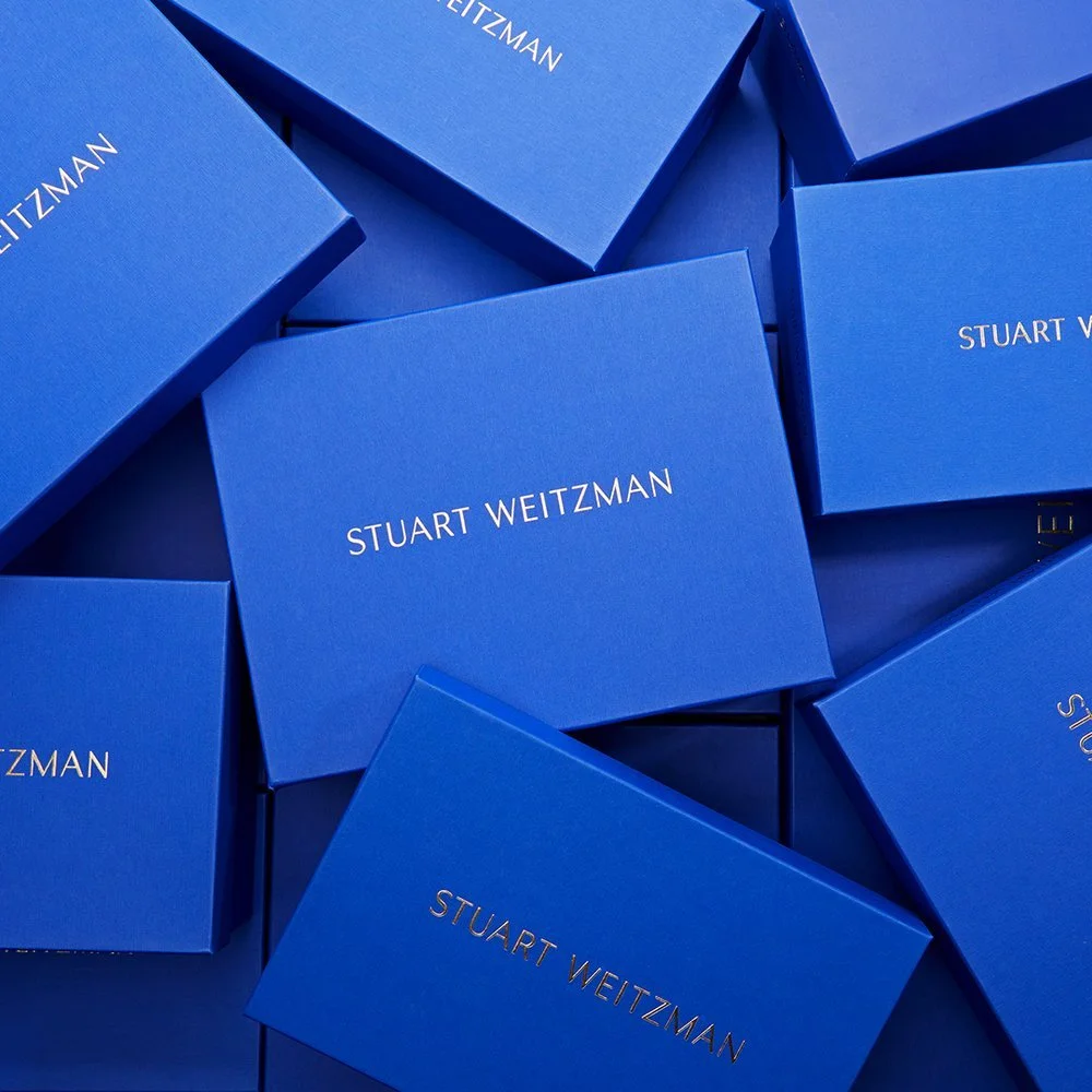 Multiple blue boxes with the name 'Stuart Weitzman' printed on them in white.
