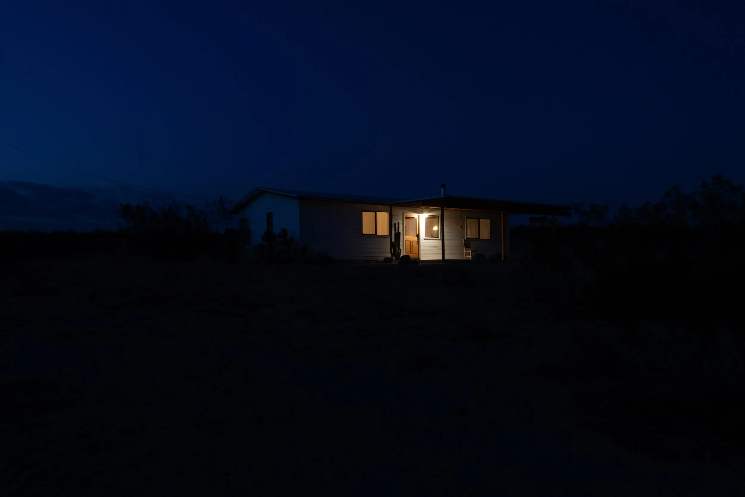 Small house with exterior lights on at night in a rural area