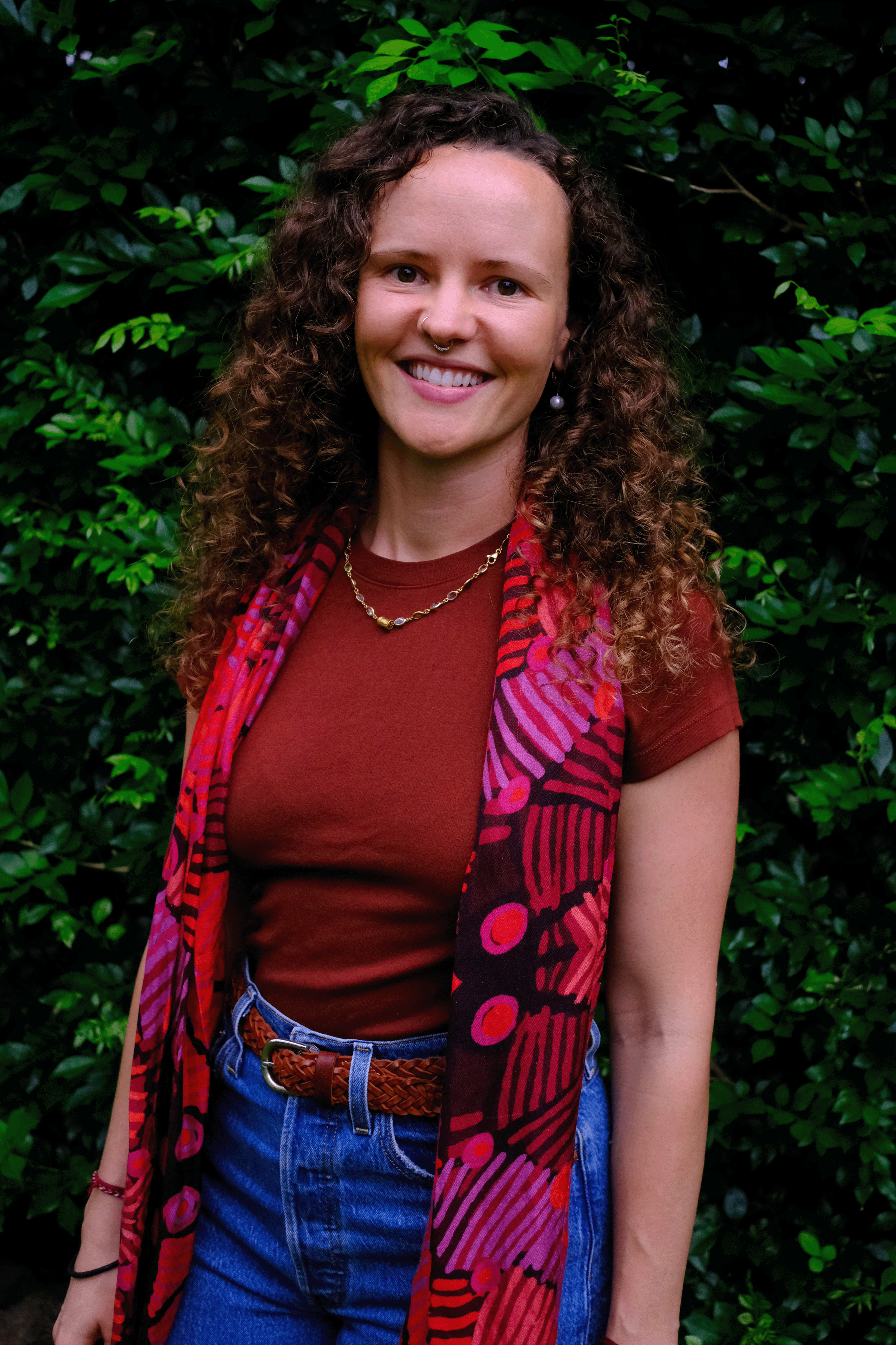 Smiling woman wearing red top and scarf and blue jeans
