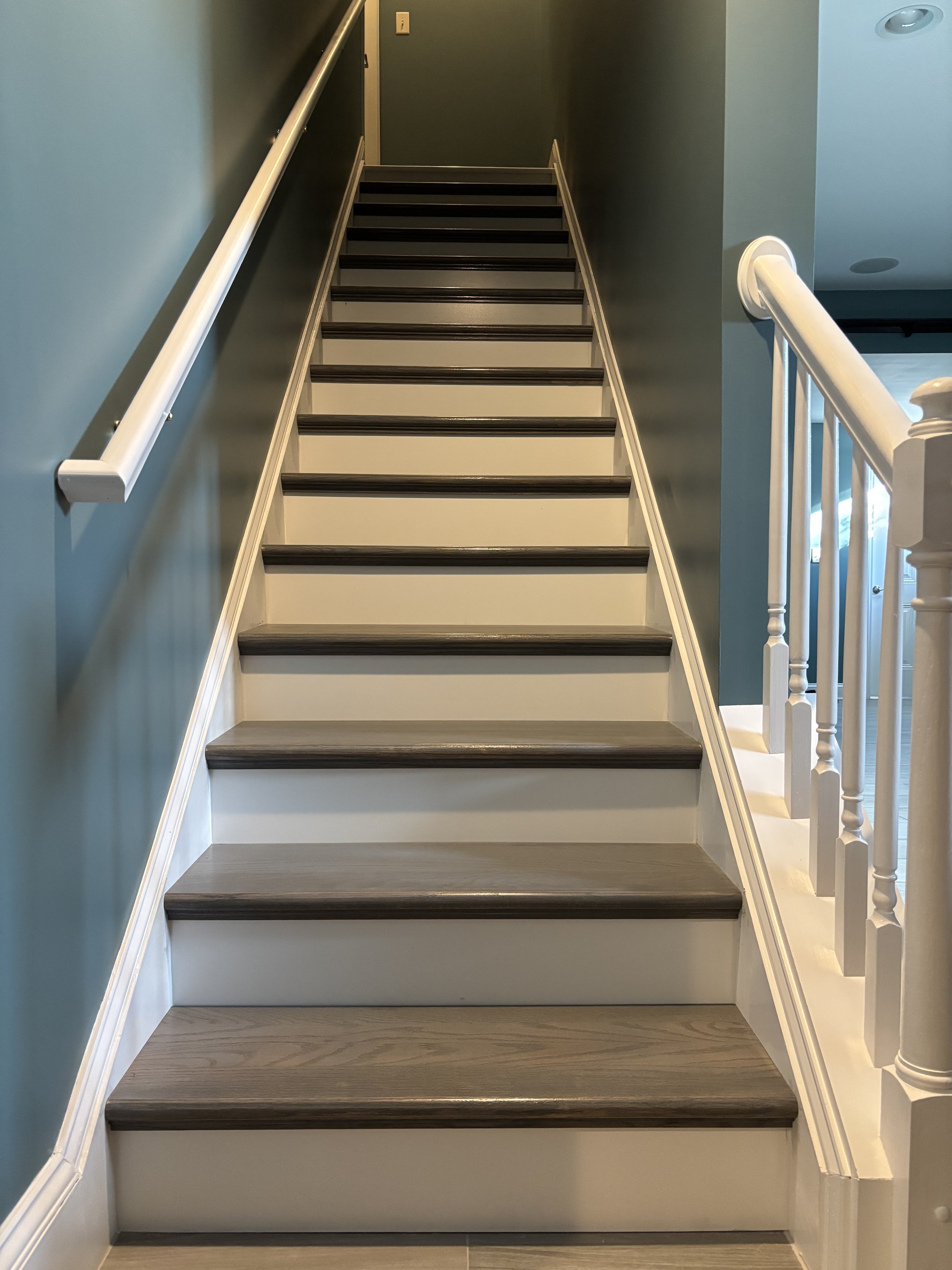 Staircase refinishing in Lancaster County featuring new tread boards and risers, white-painted risers,and stained wood treads.