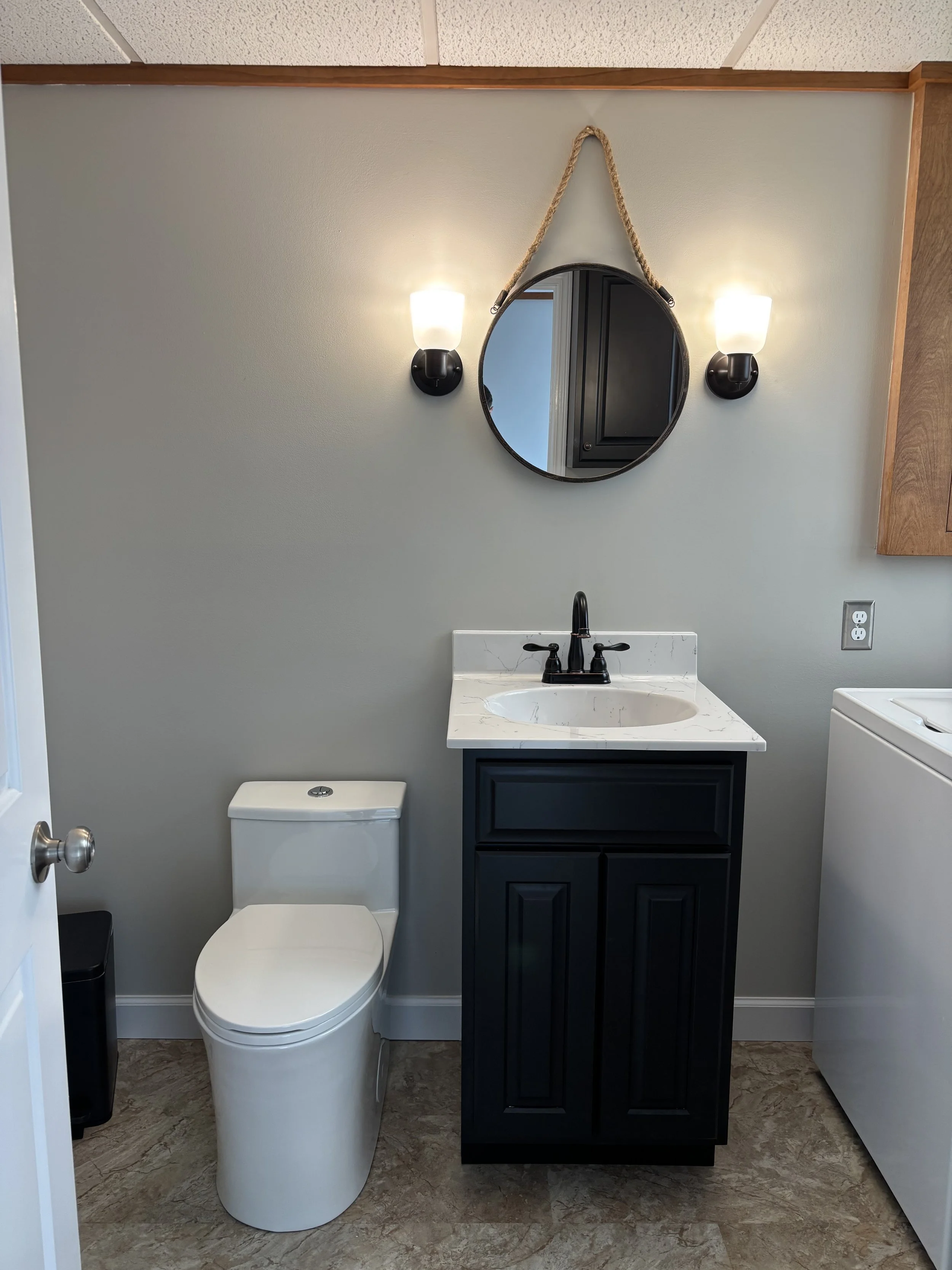 New toilet, vanity, faucet, and plumbing fixtures installed in a laundry room