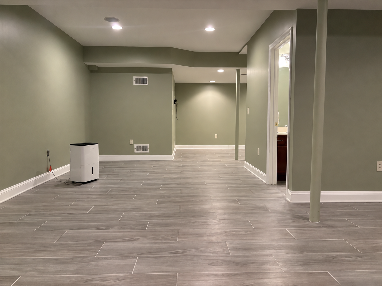 Basement restoration in Lancaster County featuring drywall replacement and finishing, interior painting, tile flooring, baseboards, and quarter-round trim.