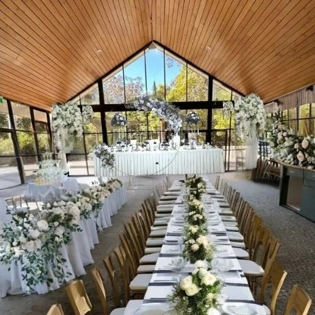 Elegant wedding venue with floral decorations, long tables, and large windows.