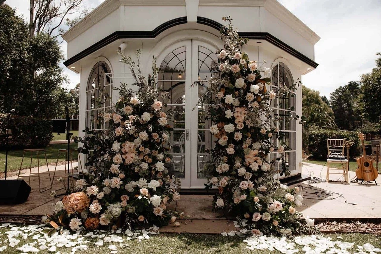 Outdoor wedding venue with floral arrangements and a small white building