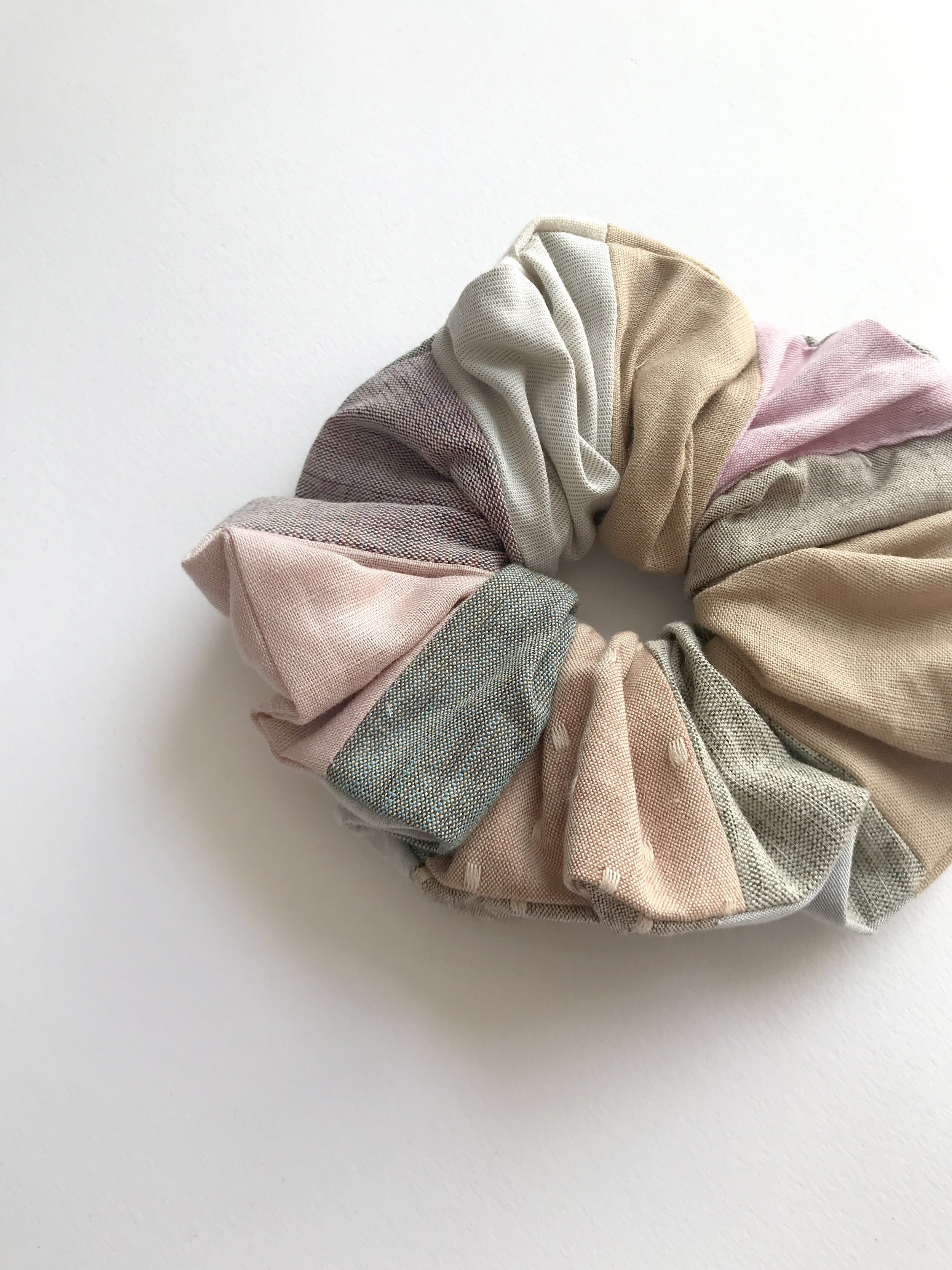 Close up of a cotton and linen patchwork scrunchie in mismatching blue cotton fabrics