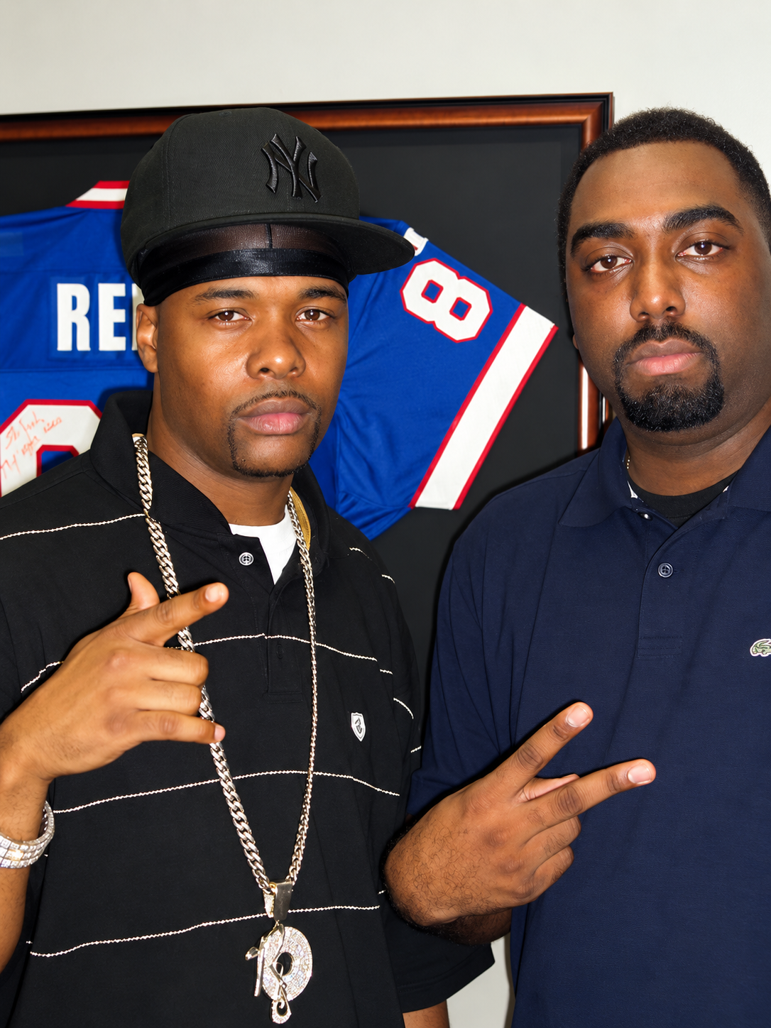 Two Men Before a Framed Football Jersey.png