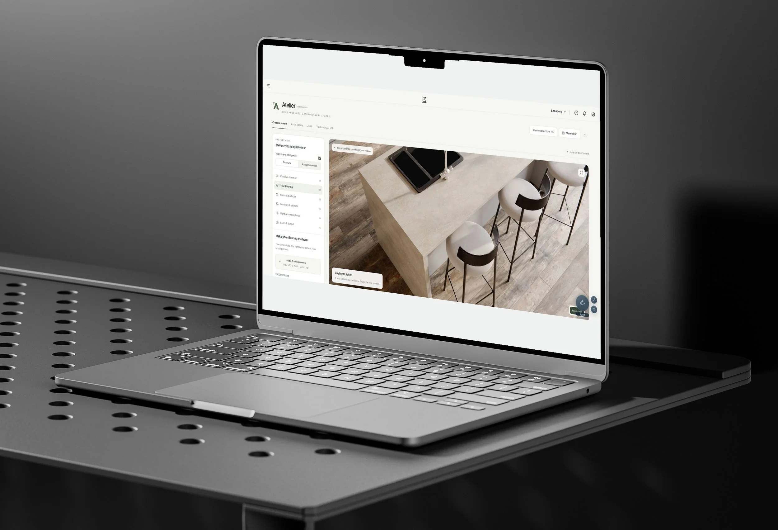 Lenscore Atelier displayed on an angled MacBook on a black perforated table, showing the Daylight kitchen template and scene controls.