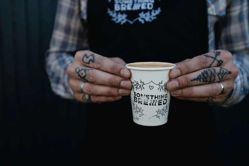 Barista holding artisan specialty coffee at a converted barn venue in Scotland
