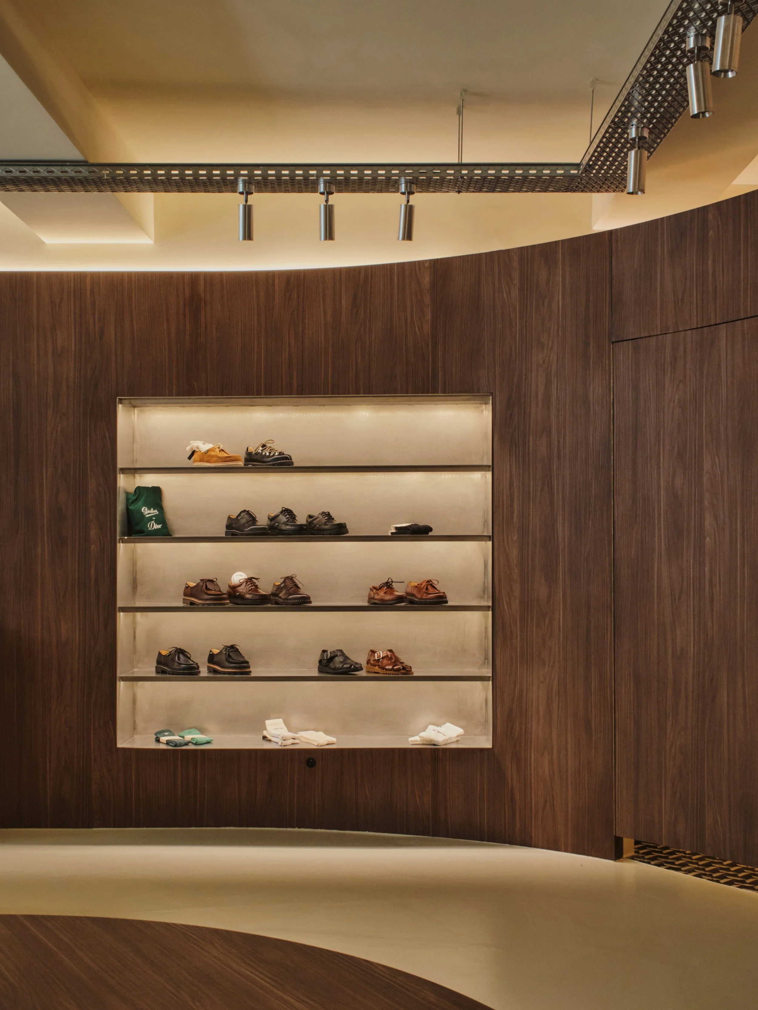 Etagère inox dans un mur en bois foncé dans une boutique de vêtements homme haut de gamme 