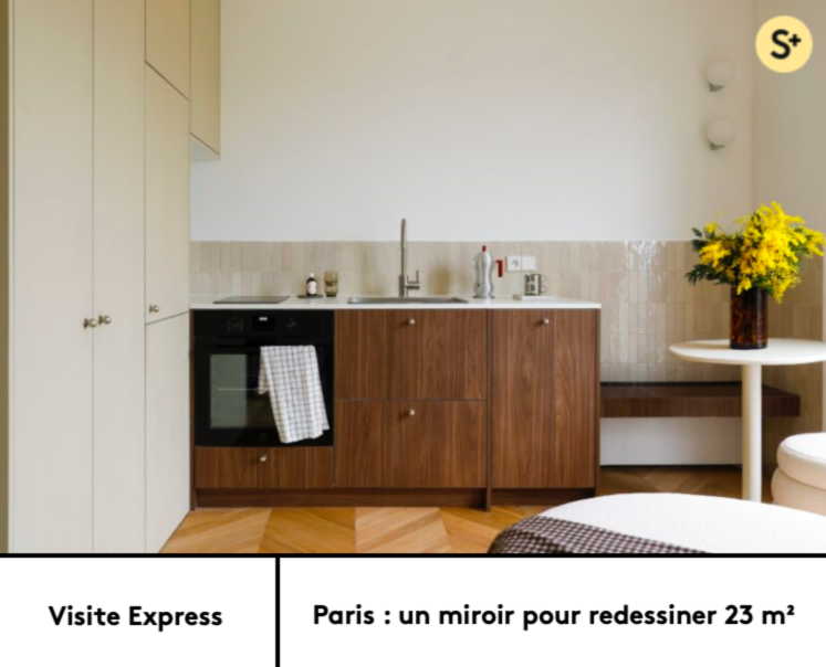 Une cuisine minimaliste avec des meubles en bois foncé, une cuisine intégrée, un évier, un four noir avec une serviette en tissu à carreaux suspendue, et une petite table ronde blanche avec un vase de fleurs jaunes.
