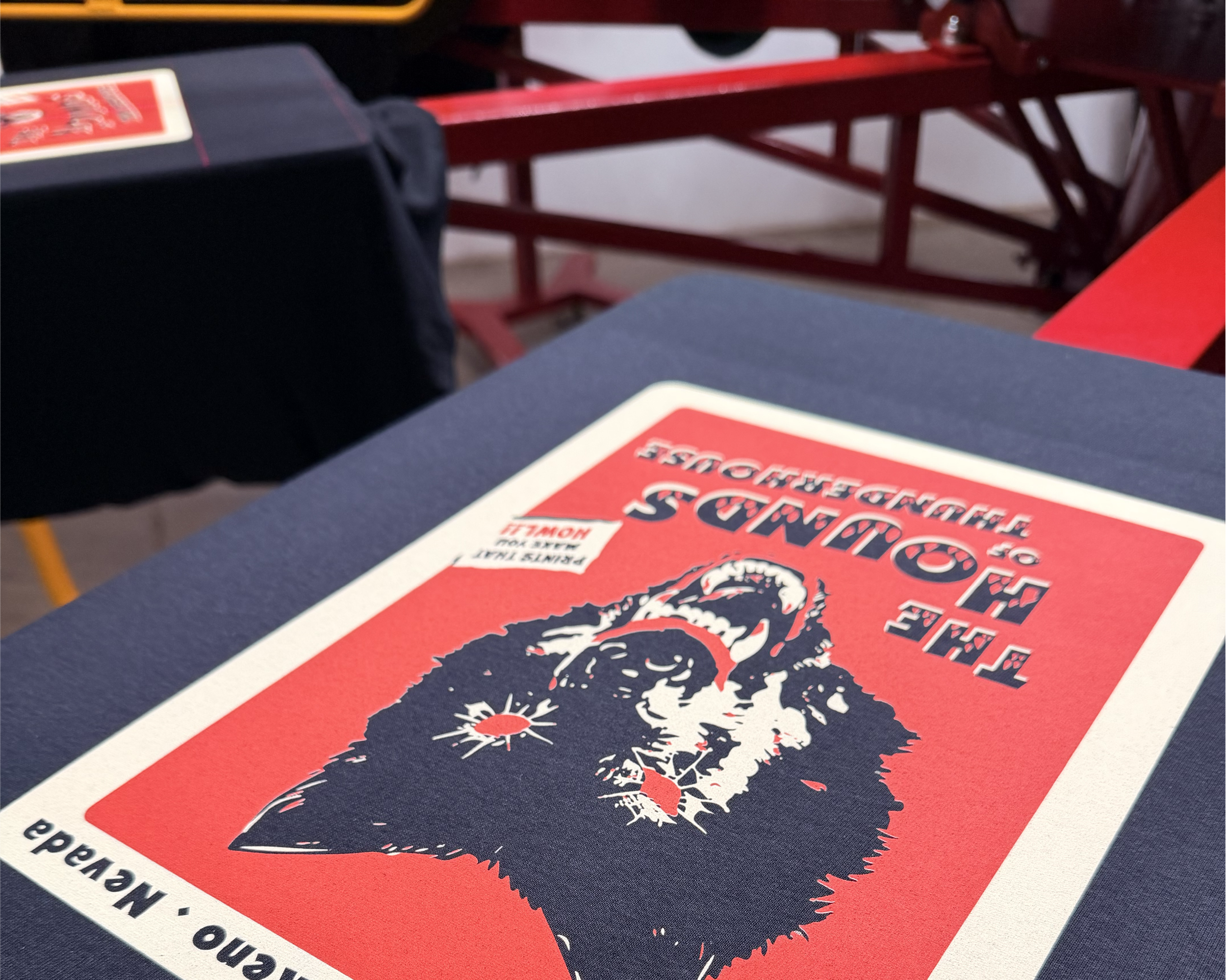 An anatol auto screen printing press with a black tee shirt being printed with a wolf in red and cream. thunder house screen printing reno, NV
