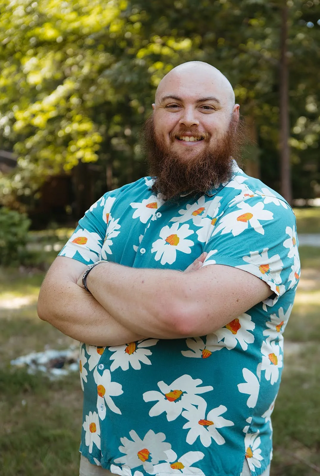 A smiling man with a beard and bald head, wearing a gray shirt, sitting in front of a brick wall. Tennessee Placenta Services Team. 