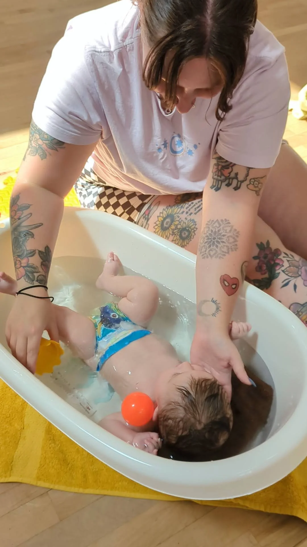 A mum bathing her baby while using a sprinkle cup