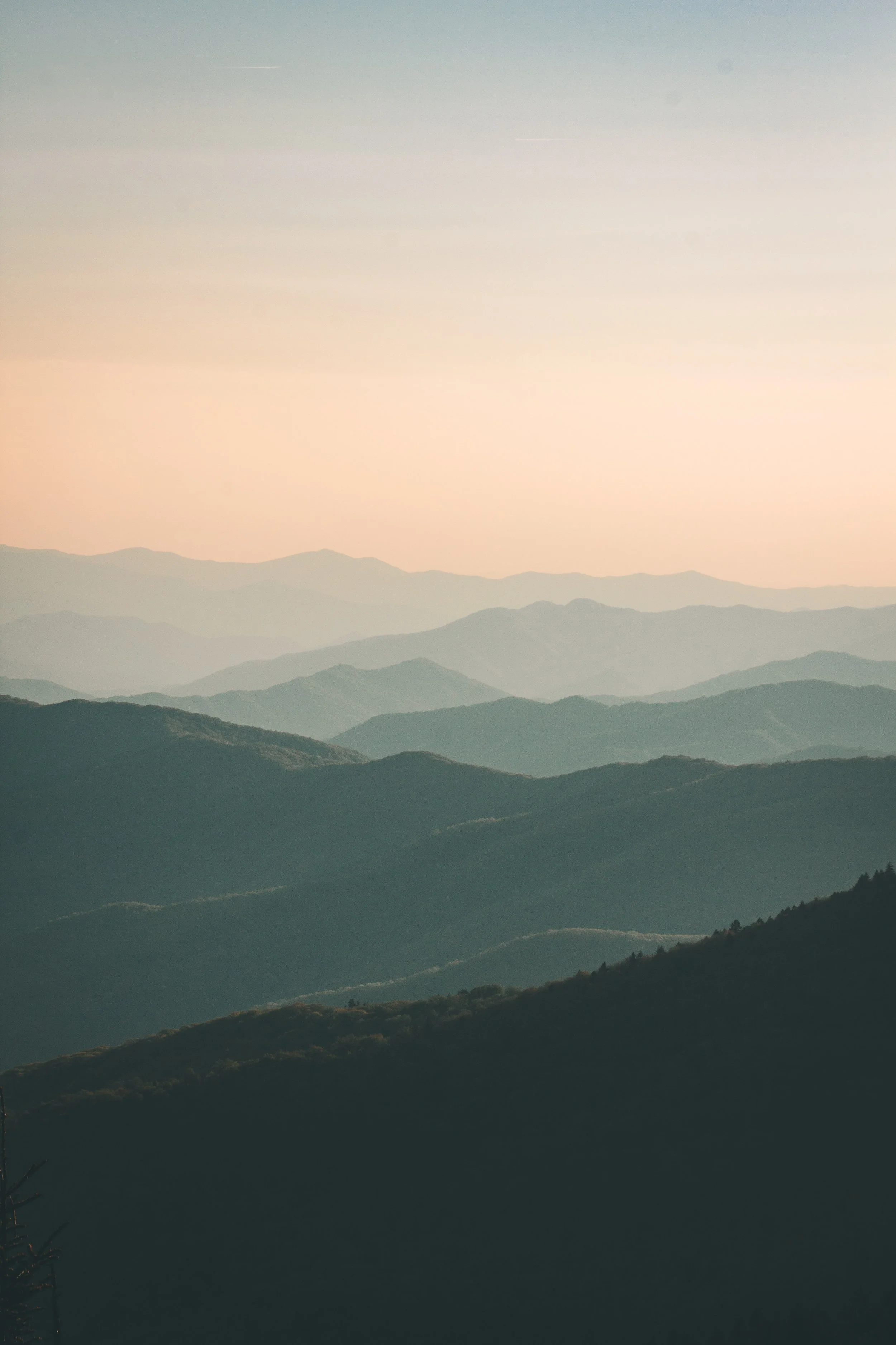 Layered mountain landscape under a hazy sky at dawn or dusk.