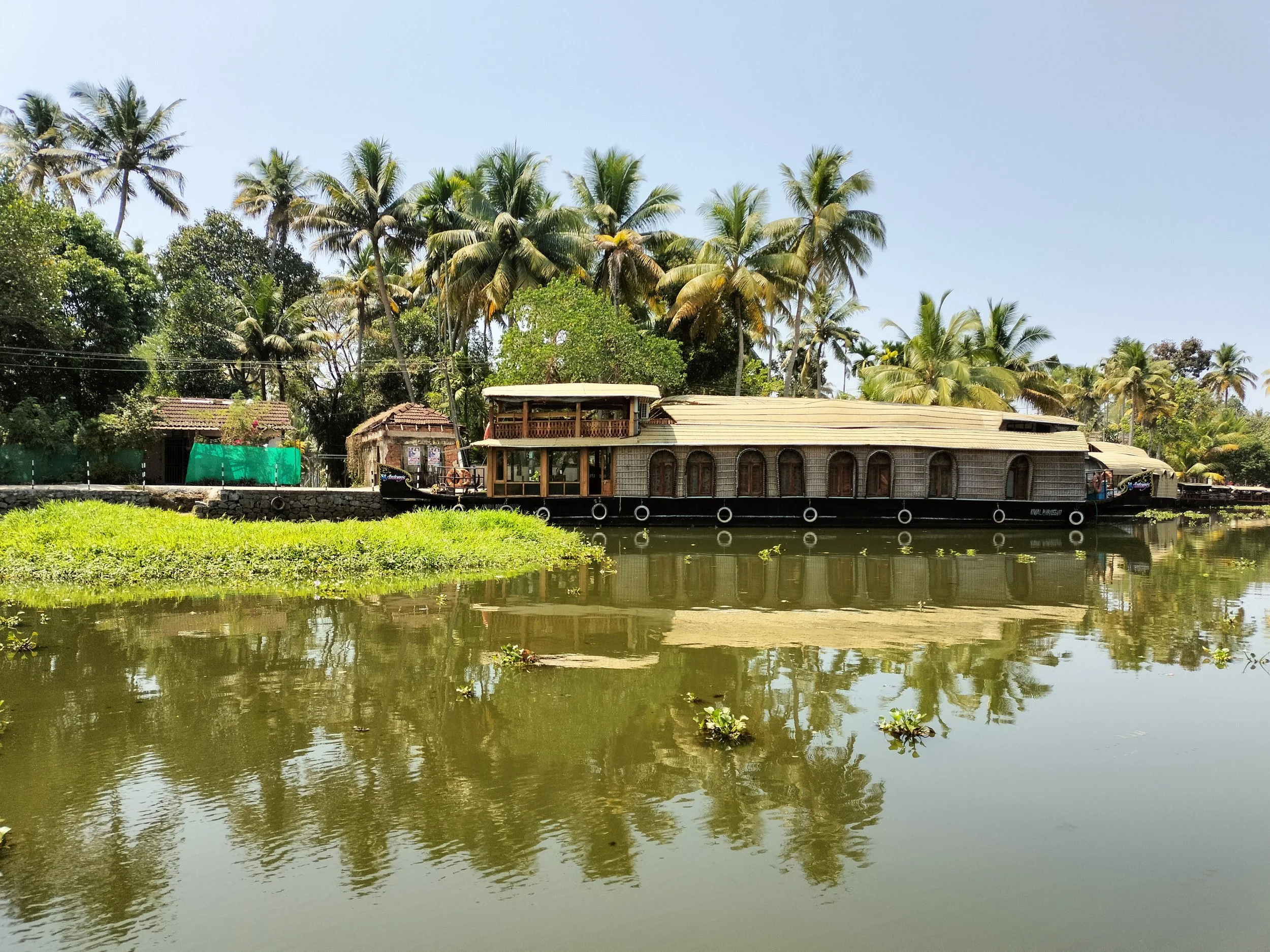 Casa flotante de madera en un río rodeada de palmeras y vegetación tropical