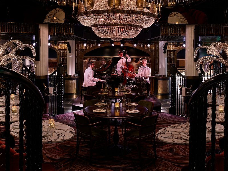 Musicians performing jazz in an elegant restaurant with a chandelier, marble floor, and decorated walls.