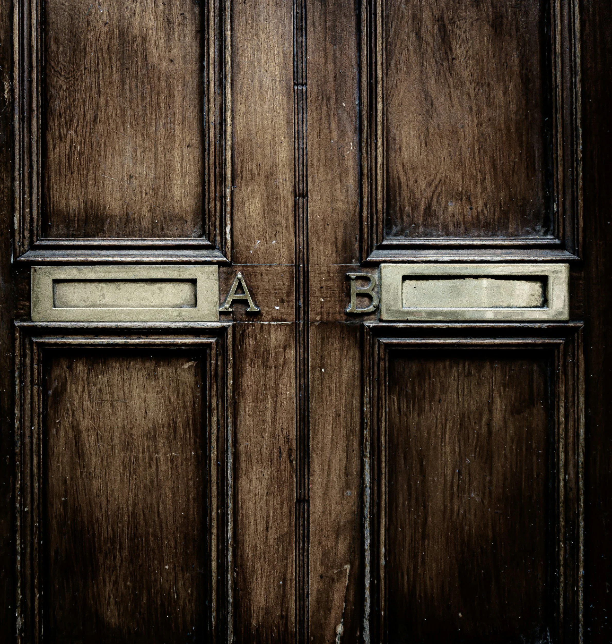 Old wooden cabinet with wooden panels and metal letter slots labeled A and B.