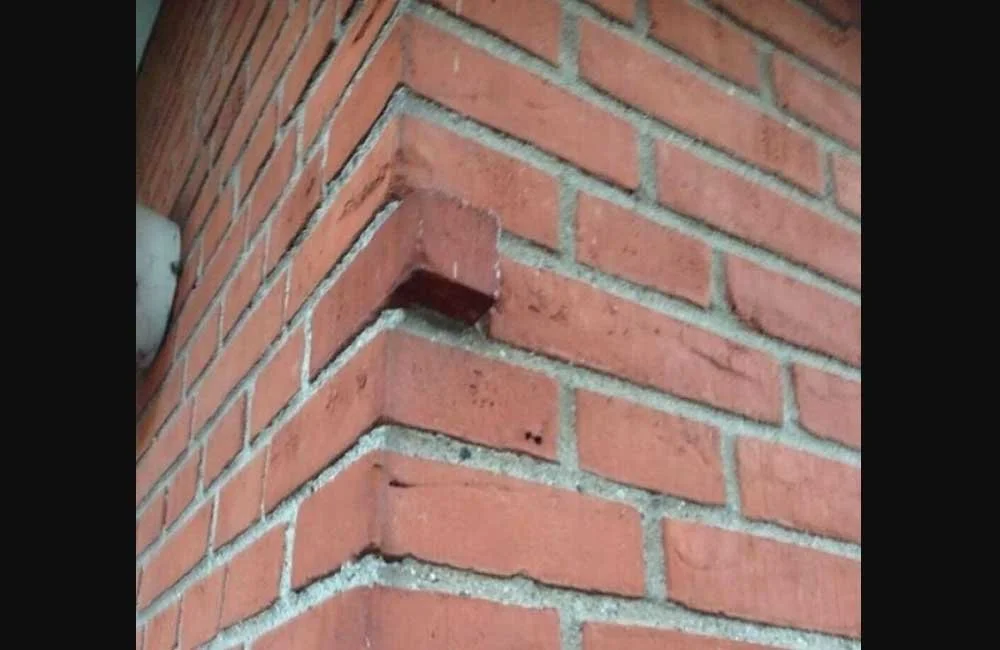 Close-up of a corner of a brick wall showing a missing brick at the corner.