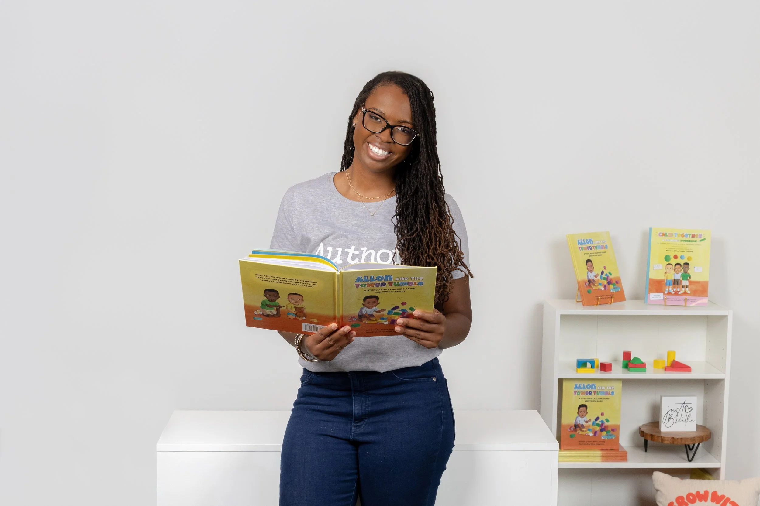 African-American female children's book author smiling at the camera holding her book open during her personal branding session