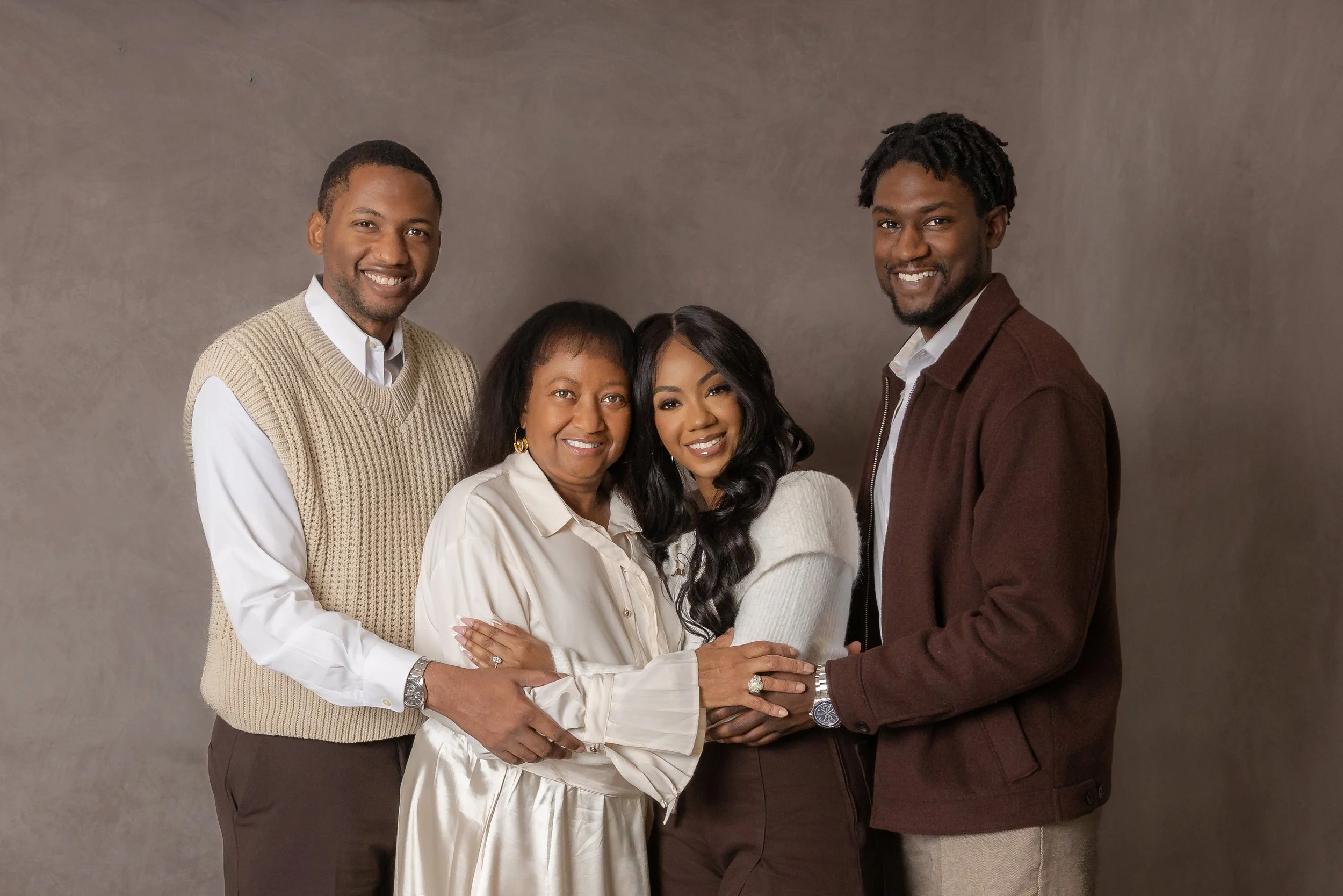 Black family of four laughing together during an in-studio family photo session in Burleson, Texas.