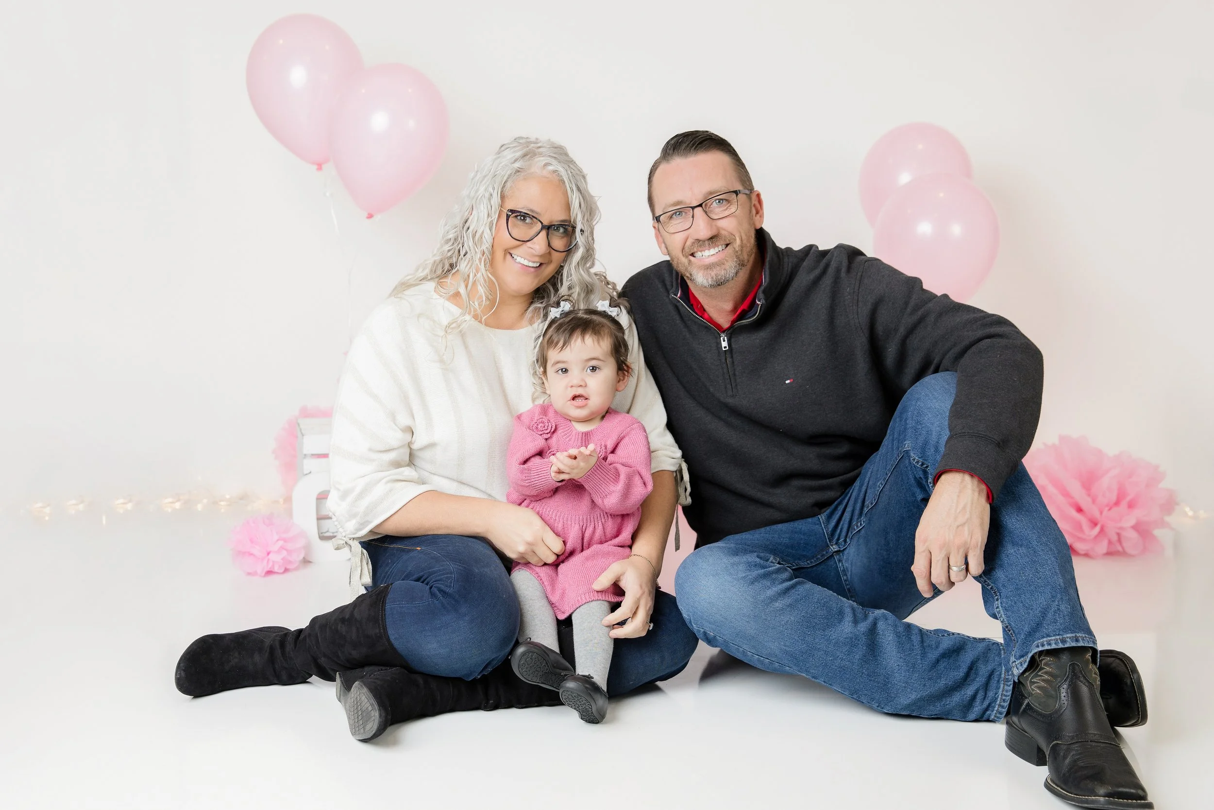 Mom and Dad with one year old daughter during cake smash in-studio photo session in Burleson, TX