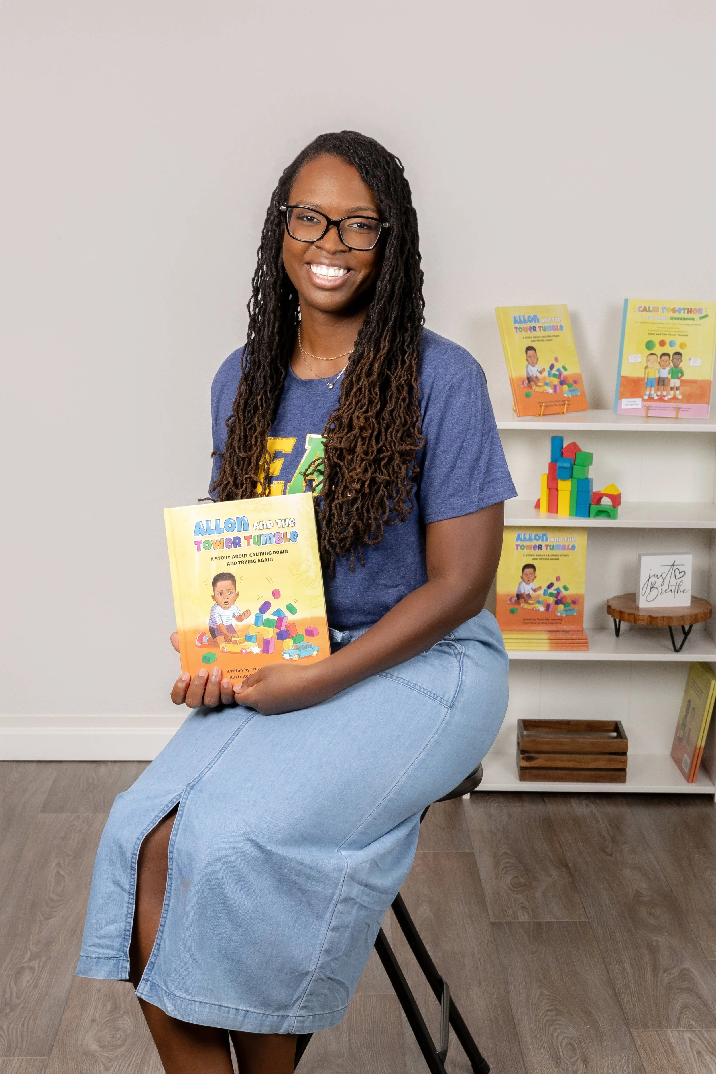 African-American female children's book author smiling at the camera holding her book during her personal branding session