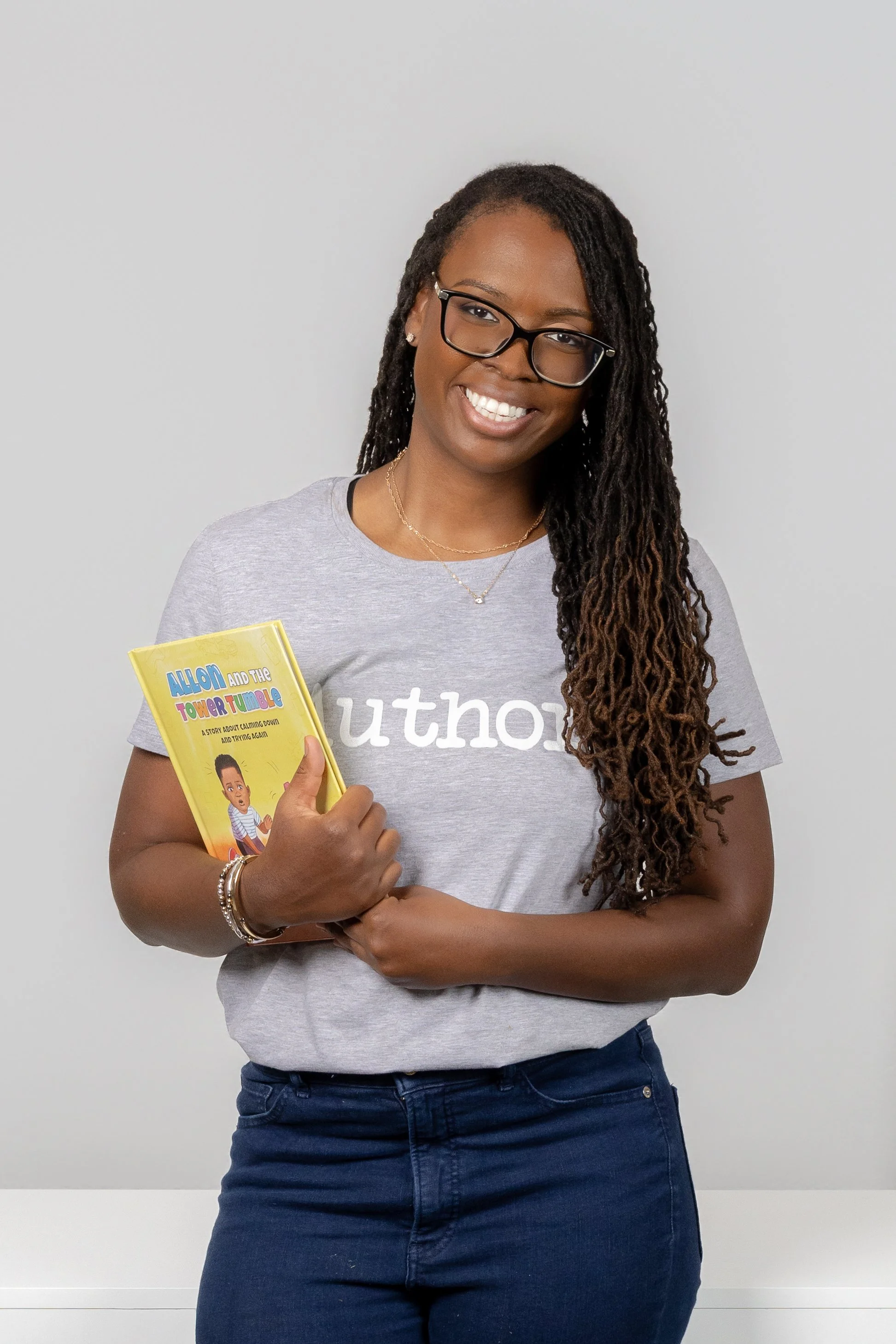 African-American female children's book author smiling at the camera holding her book during her personal branding session