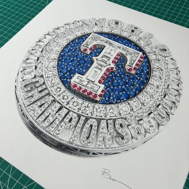 A decorative, round piece with a large letter ‘T’ in the center, surrounded by multiple blue and red gemstones, and an outer ring of clear, diamond-like stones, on white paper.