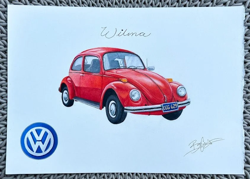 A napkin featuring a red vintage Volkswagen Beetle, the word 'Wilma' written at the top, and the Volkswagen logo at the bottom left corner.