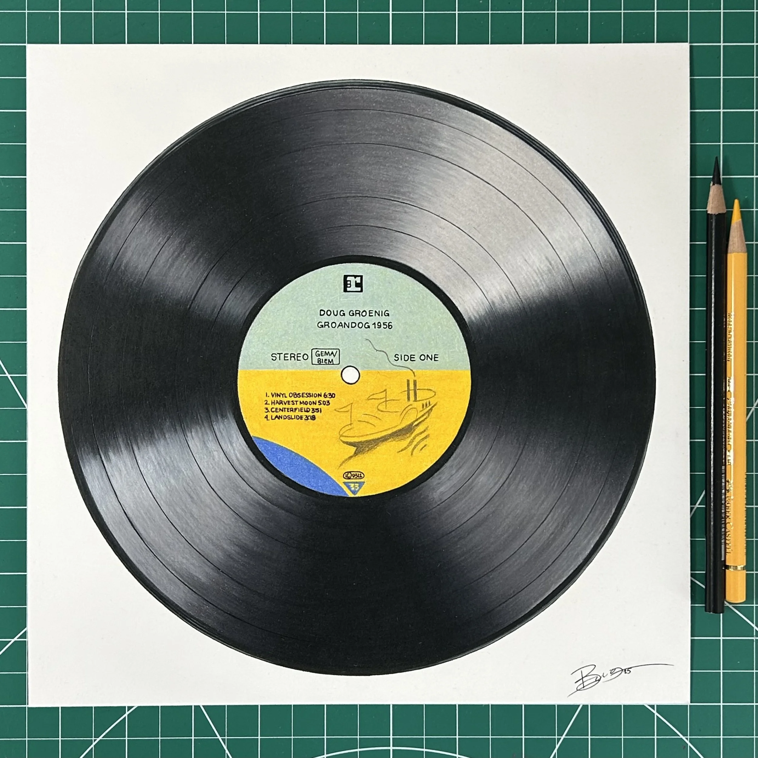 A black vinyl record with a yellow and green label, placed on a white background, with two pencils on the right side and a signature at the bottom right corner.