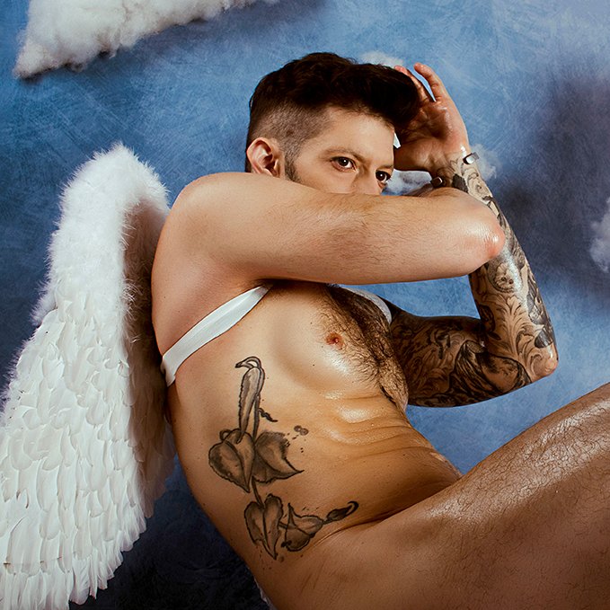 Gay photography by Ceraun the Divanun featuring a naked gay man wearing angel wings, bent over to the side, shielding his face.