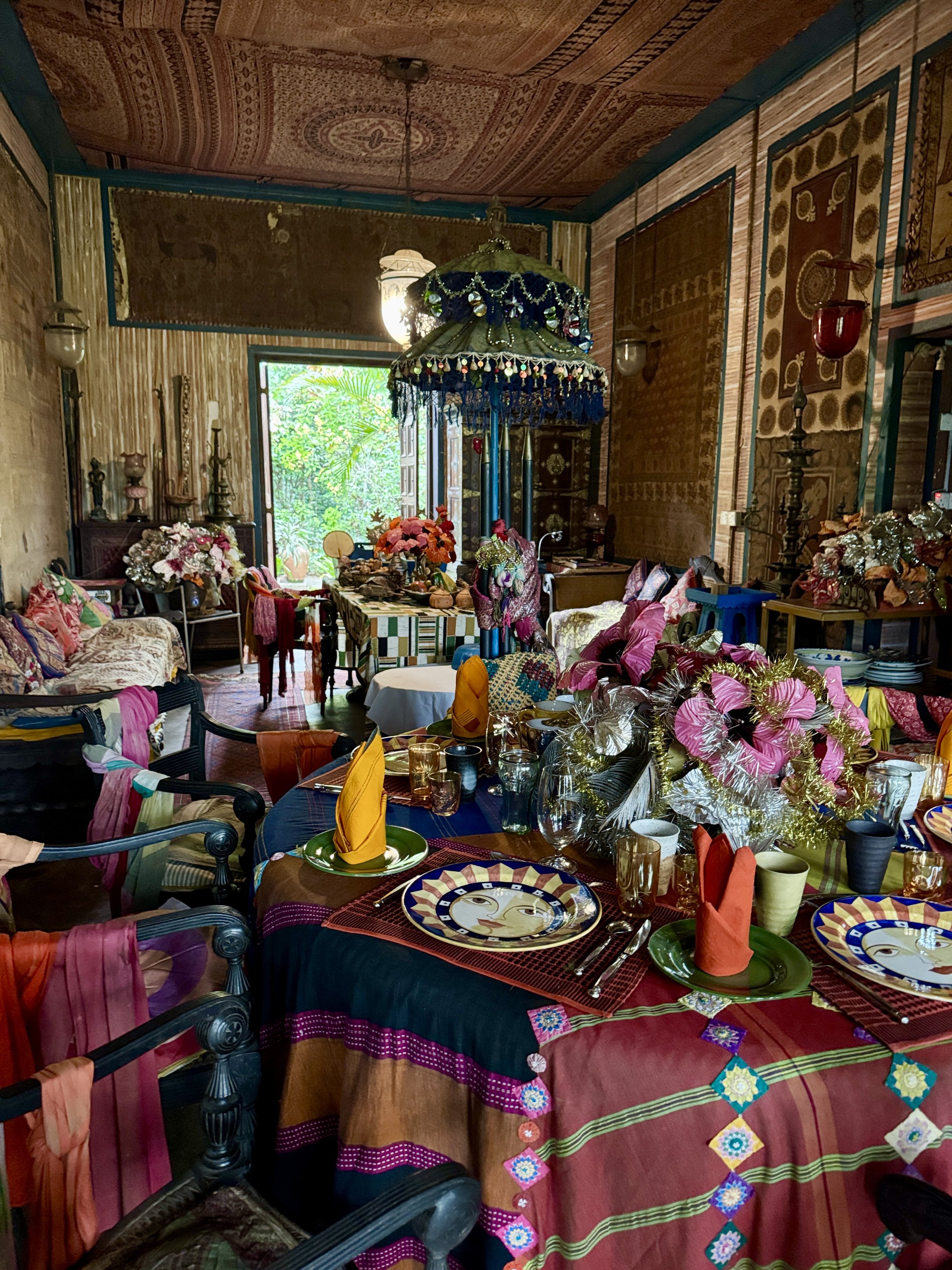 The interior of Sri Lankan artist Ena de Silva's house with colourful fabrics, plates, flower arrangements and tapestries.