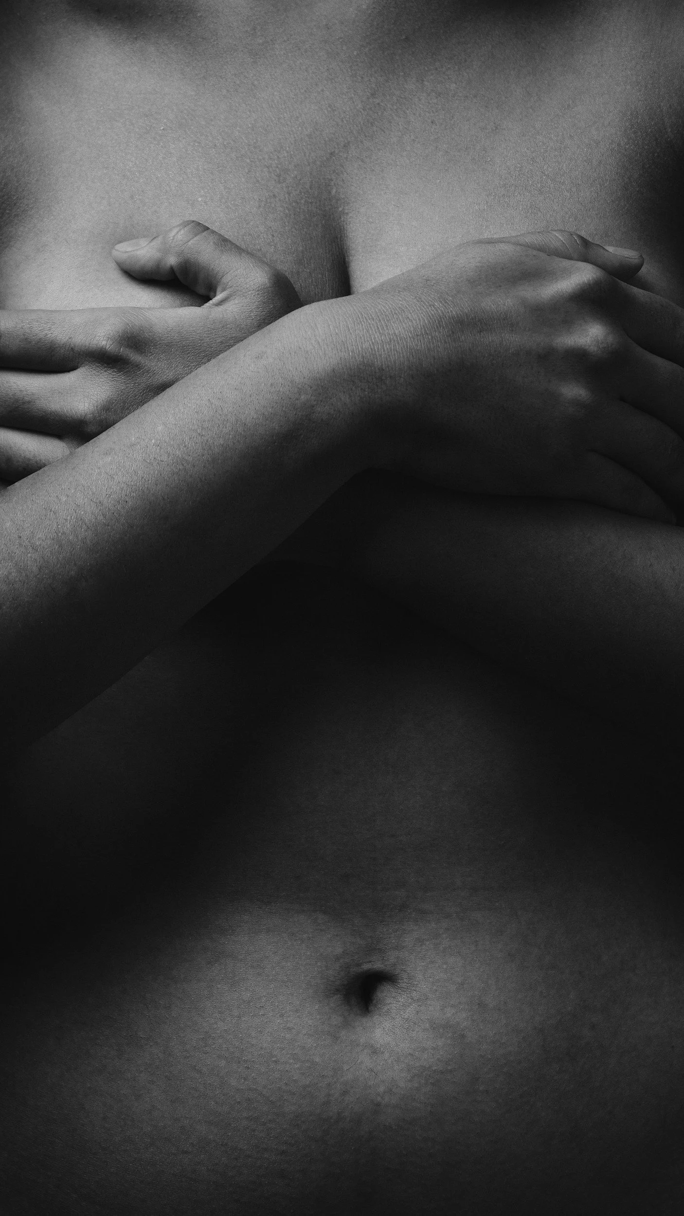 Une image en noir et blanc montrant un torse nu avec des bras croisés sur la poitrine.